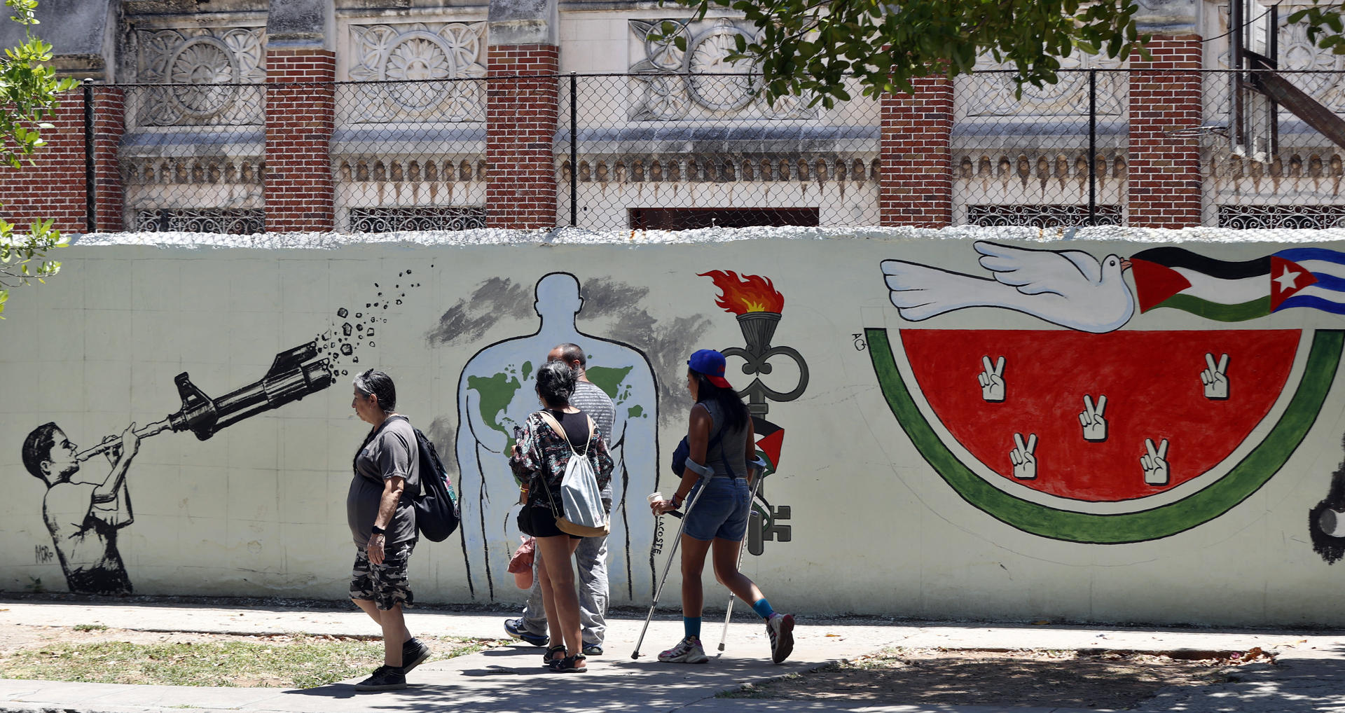 Un grupo de transeúntes fue captado este jueves, 15 de mayo, al pasar frente a un mural alusivo a la causa palestina y en memoria del 77 aniversario del inicio de la Nakba (catástrofe, en árabe), que marcó la expulsión de unos 700.000 palestinos de sus tierras forzados por milicias judías, en La Habana (Cuba). EFE/Ernesto Mastrascusa