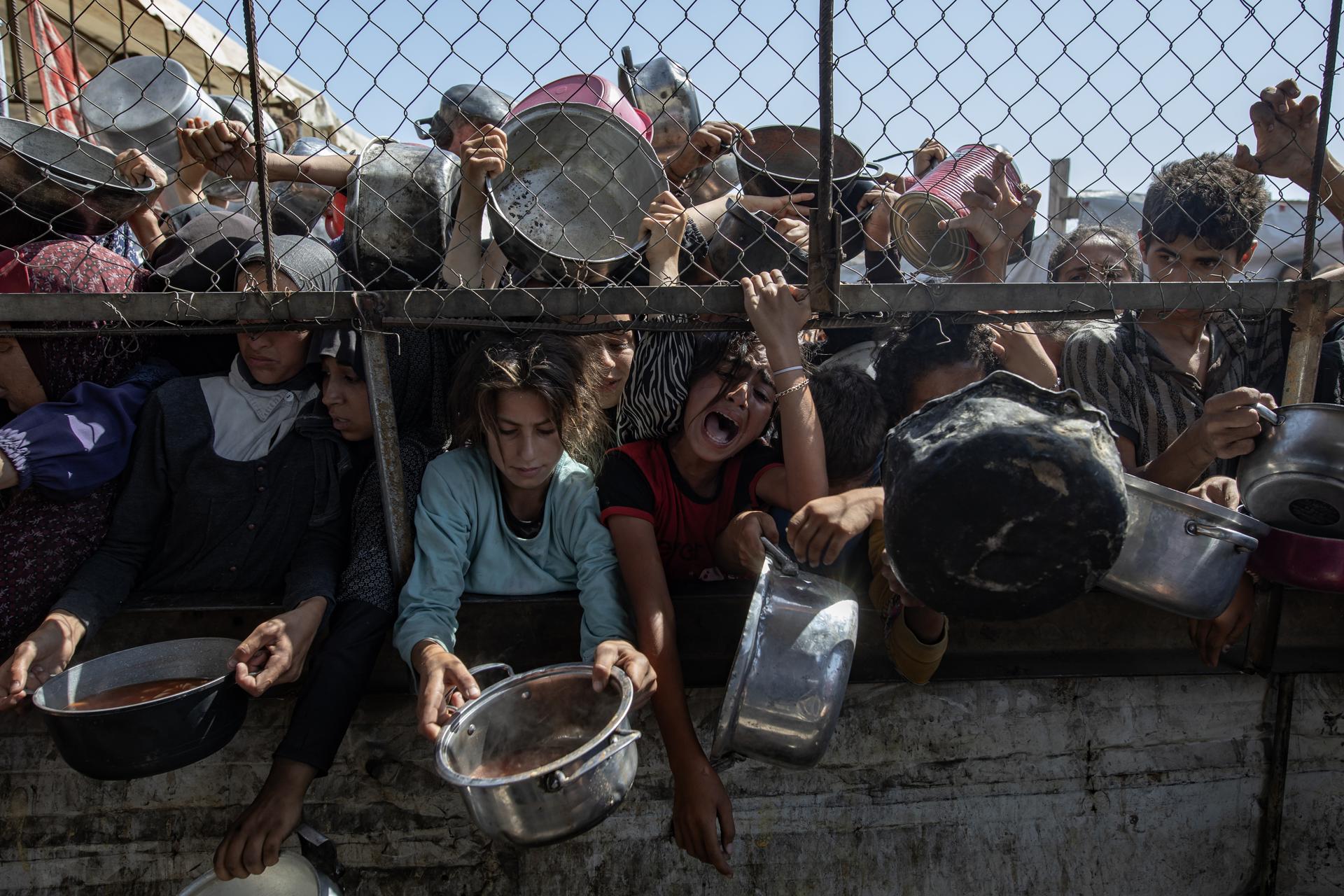 Palestinos desplazados internos se agolpan frente a un comedor social para recibir raciones limitadas ante la escasez de alimentos, en Jan Yunis, sur de la Franja de Gaza, el 30 de mayo de 2025. EFE/EPA/HAITHAM IMAD