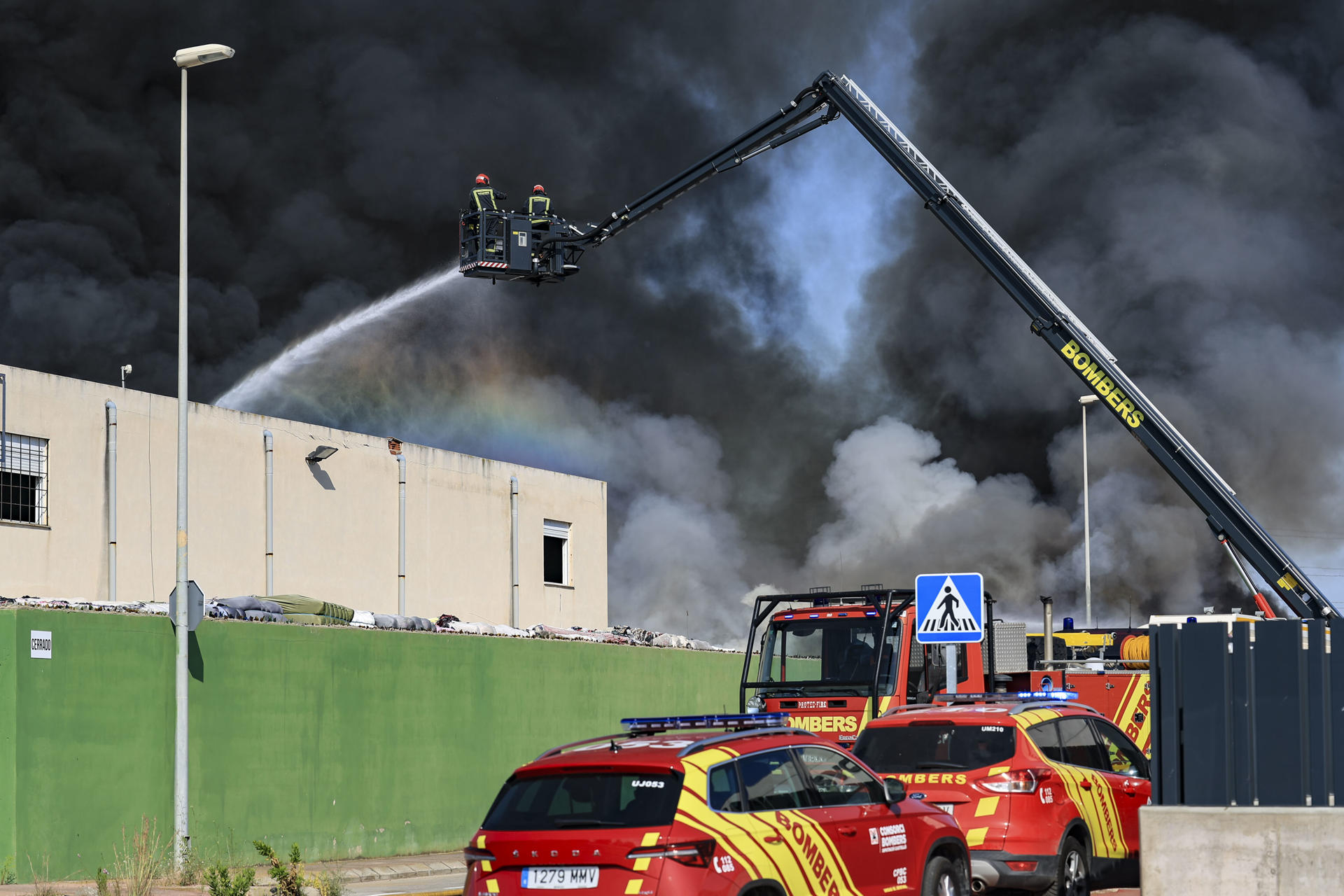Varios medios aéreos y dotaciones terrestres de bomberos trabajan en la extinción de un incendio en una nave industrial de residuos textiles en la localidad castellonense de Almassora, que ha obligado a desalojar el polígono. EFE/Andreu Esteban