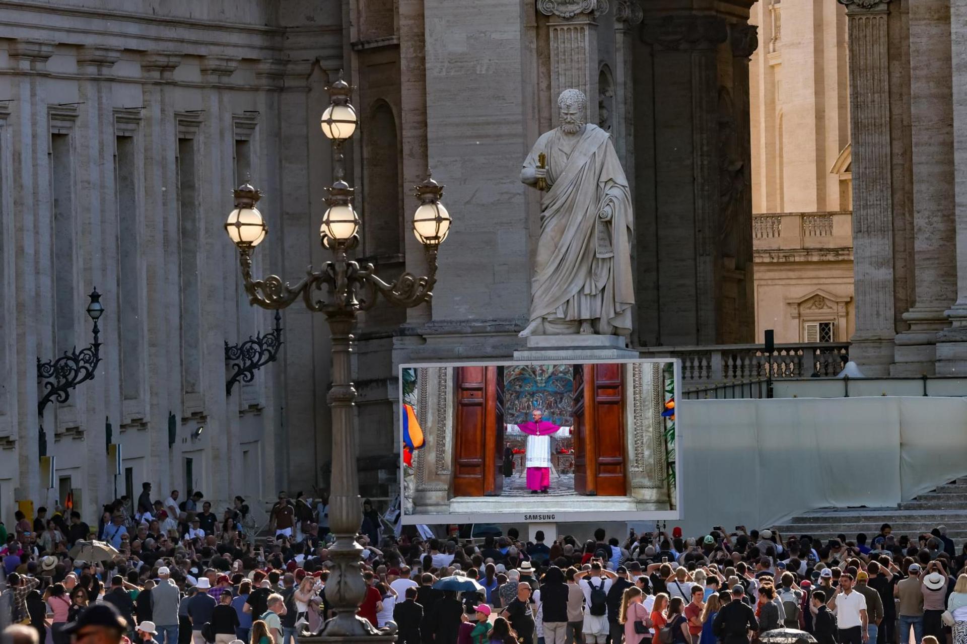 La pantalla gigante transmite imágenes del cierre de la puerta de la Capilla Sixtina, cuando comienza el cónclave para elegir al nuevo Papa, en la Plaza de San Pedro en el Vaticano, 07 de mayo de 2025. Las medidas de seguridad en la Ciudad del Vaticano han incluido el "blindaje" de la red móvil y datos en todo el Estado de la Ciudad, para evitar que los cardenales electores entren en contacto con el mundo exterior y, por lo tanto, asegurar que no haya influencia en la votación. (Papa, Cardenal) EFE/EPA/ANDREA SOLERO