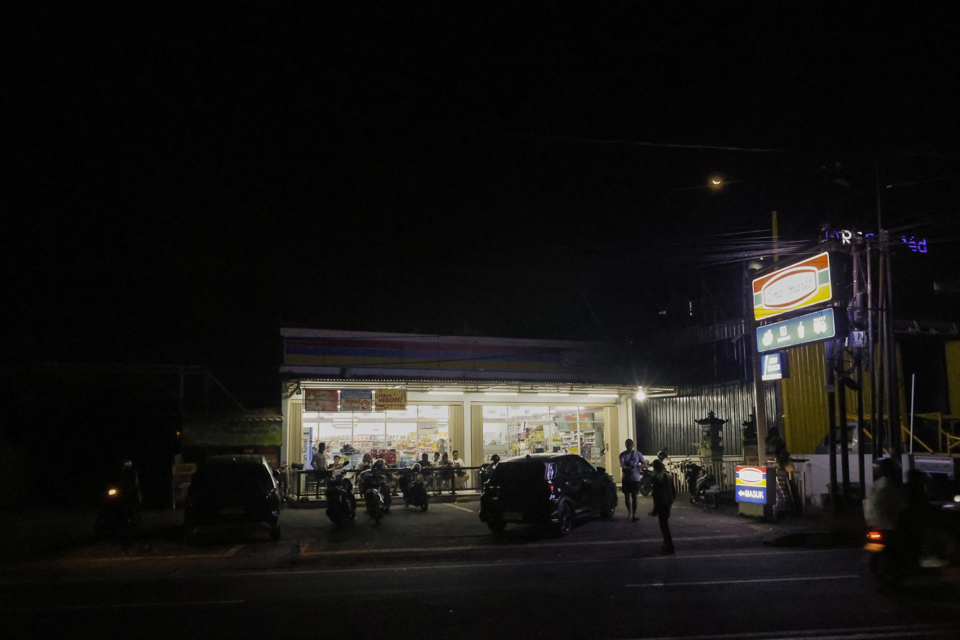 DENPASAR (Indonesia), 02/05/2025.- People gather at a convenience store that had a power generator during a power outage in Bali, Indonesia, 02 May 2025. The island of Bali experienced a total power outage or blackout on Friday, 02 May 2025, at around 4:00 PM due to a disruption in the undersea cable that transmits electricity from Java to Bali, according to officials. EFE/EPA/MADE NAGI