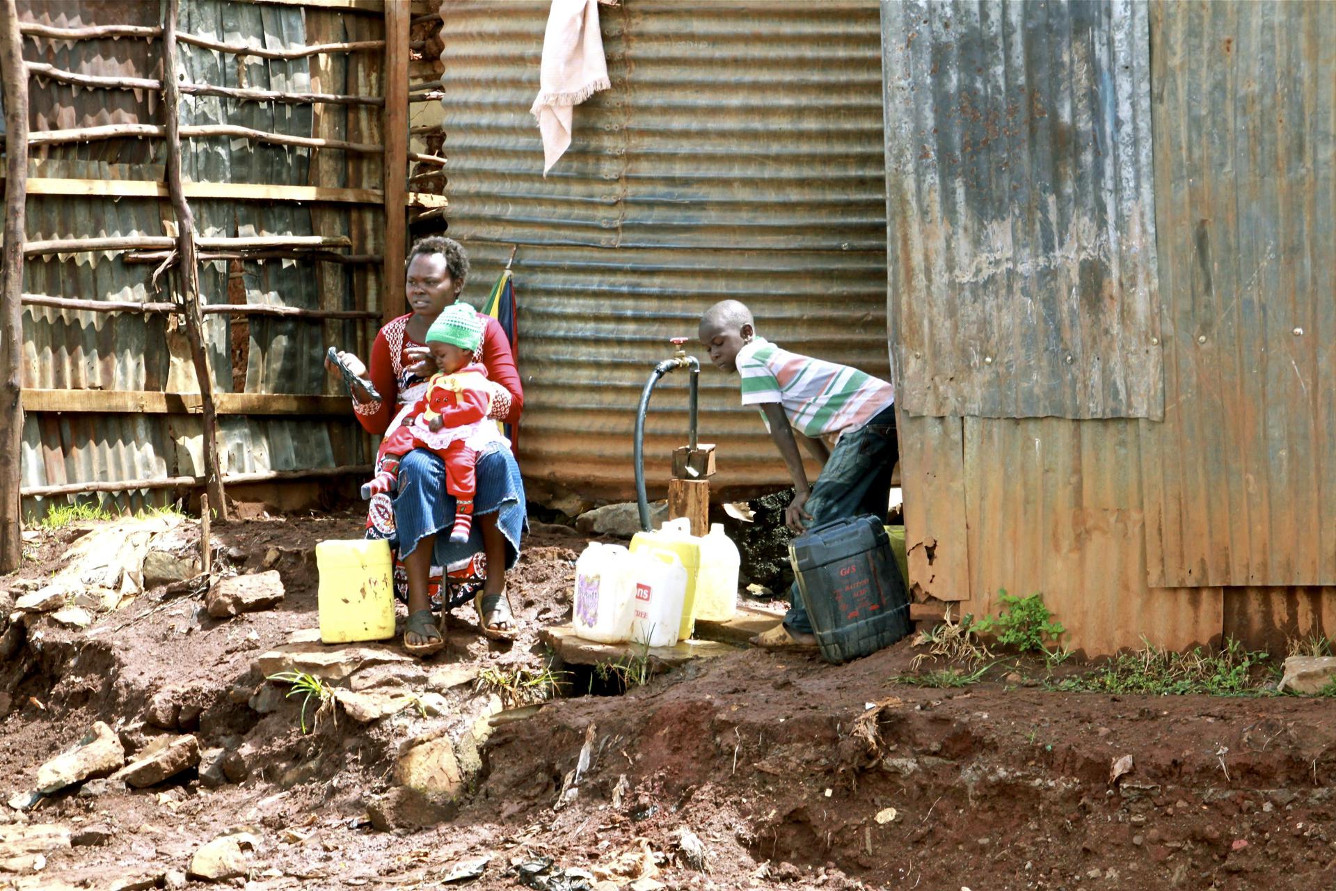 Una mujer y sus dos hijos recogen agua en bidones en uno de los distritos de Kibera (Kenia), en una imagen de archivo. EFE/José Miguel Calatayud