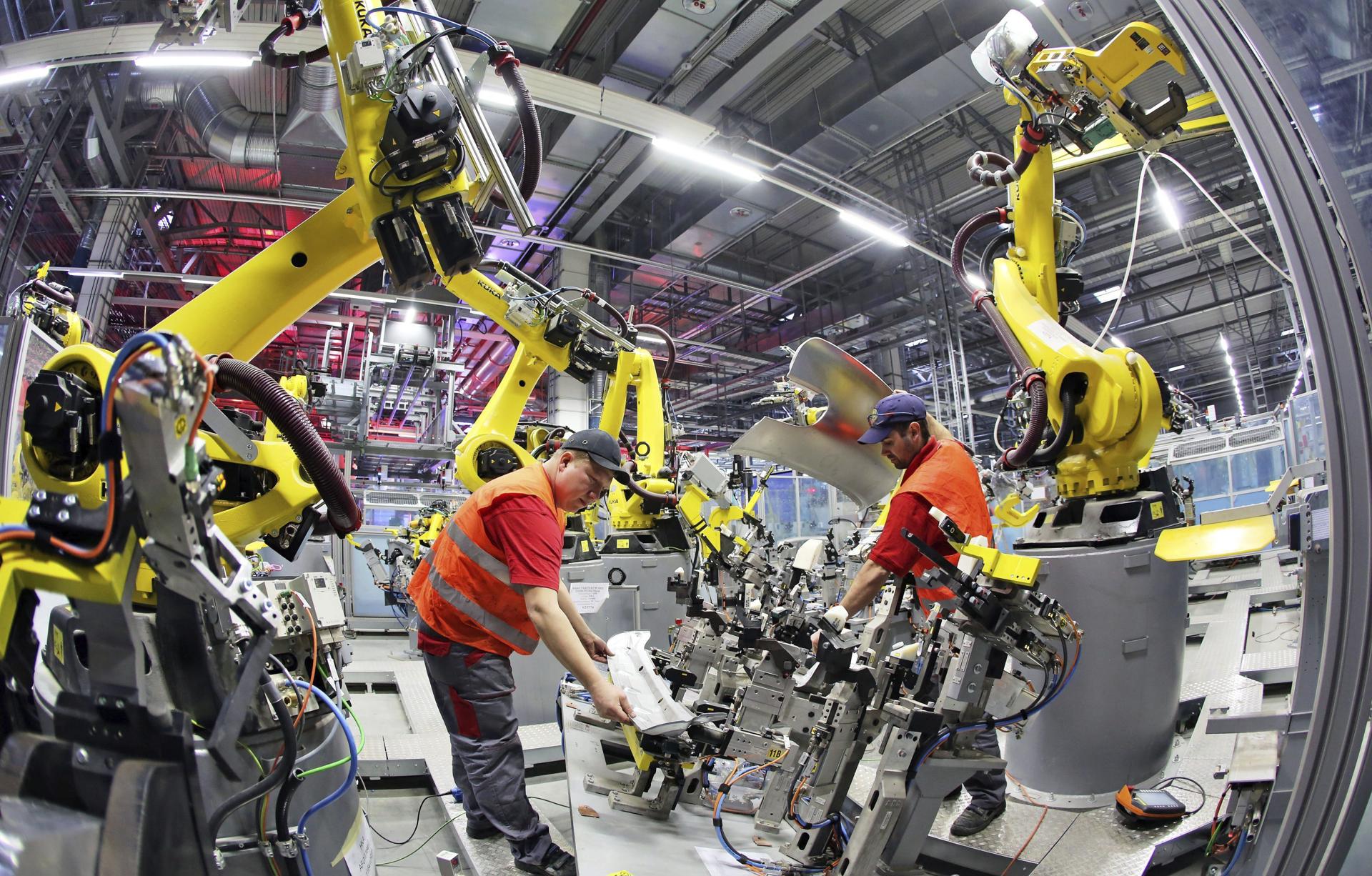 Dos ingenieros instalan un robot en la fábrica de Porsche en Leipzig, Alemania, en una imagen de archivo. EFE/Jan Woitas