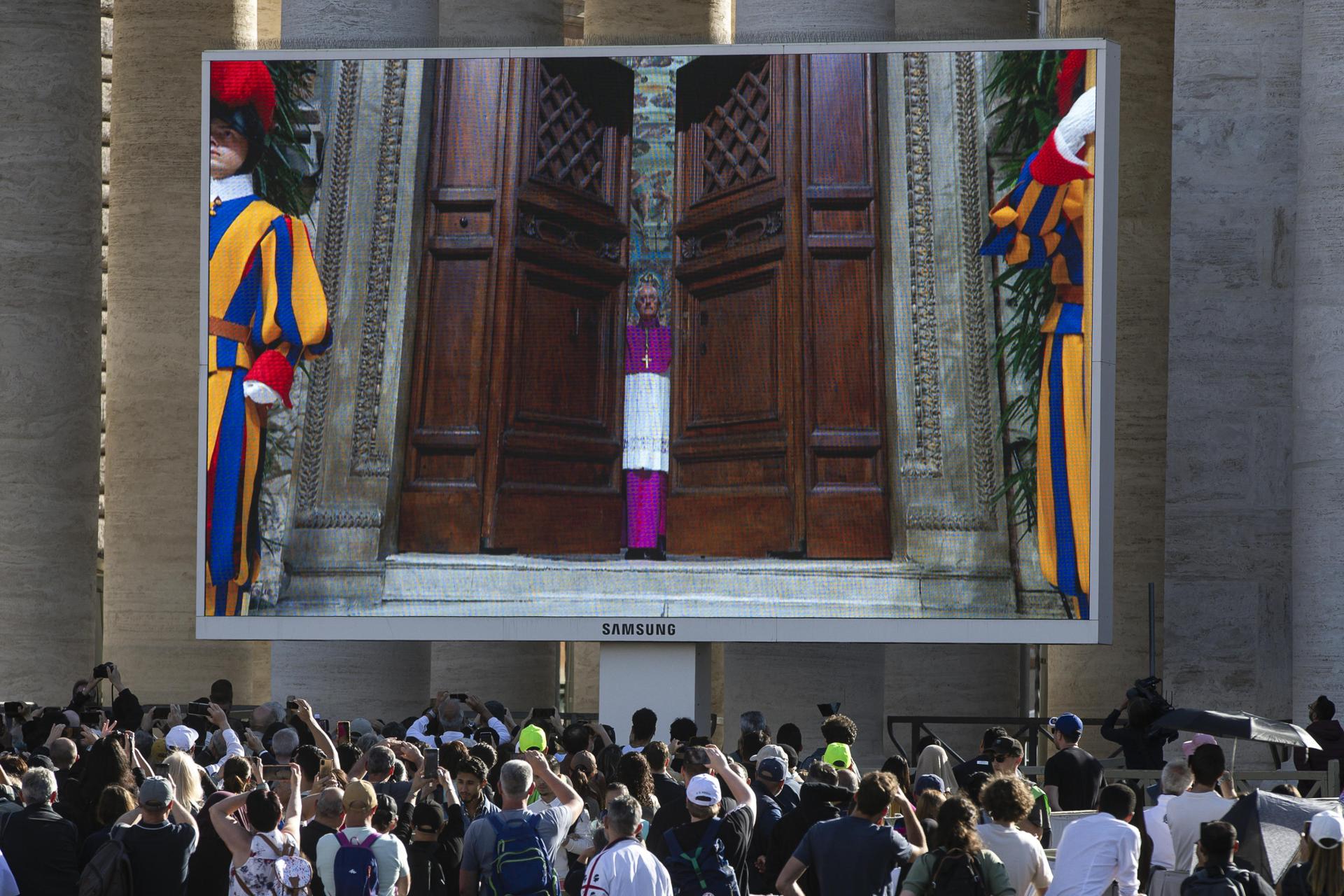 La pantalla gigante transmite imágenes del cierre de la puerta de la Capilla Sixtina, al inicio del cónclave para elegir al nuevo Papa, en la Plaza de San Pedro del Vaticano, este miércoles. Las medidas de seguridad en la Ciudad del Vaticano han incluido el blindaje de la red móvil y de datos en toda la Ciudad Estado, para evitar que los cardenales electores entren en contacto con el exterior y, por lo tanto, garantizar que no haya influencia en el voto..
EFE/ Angelo Carconi