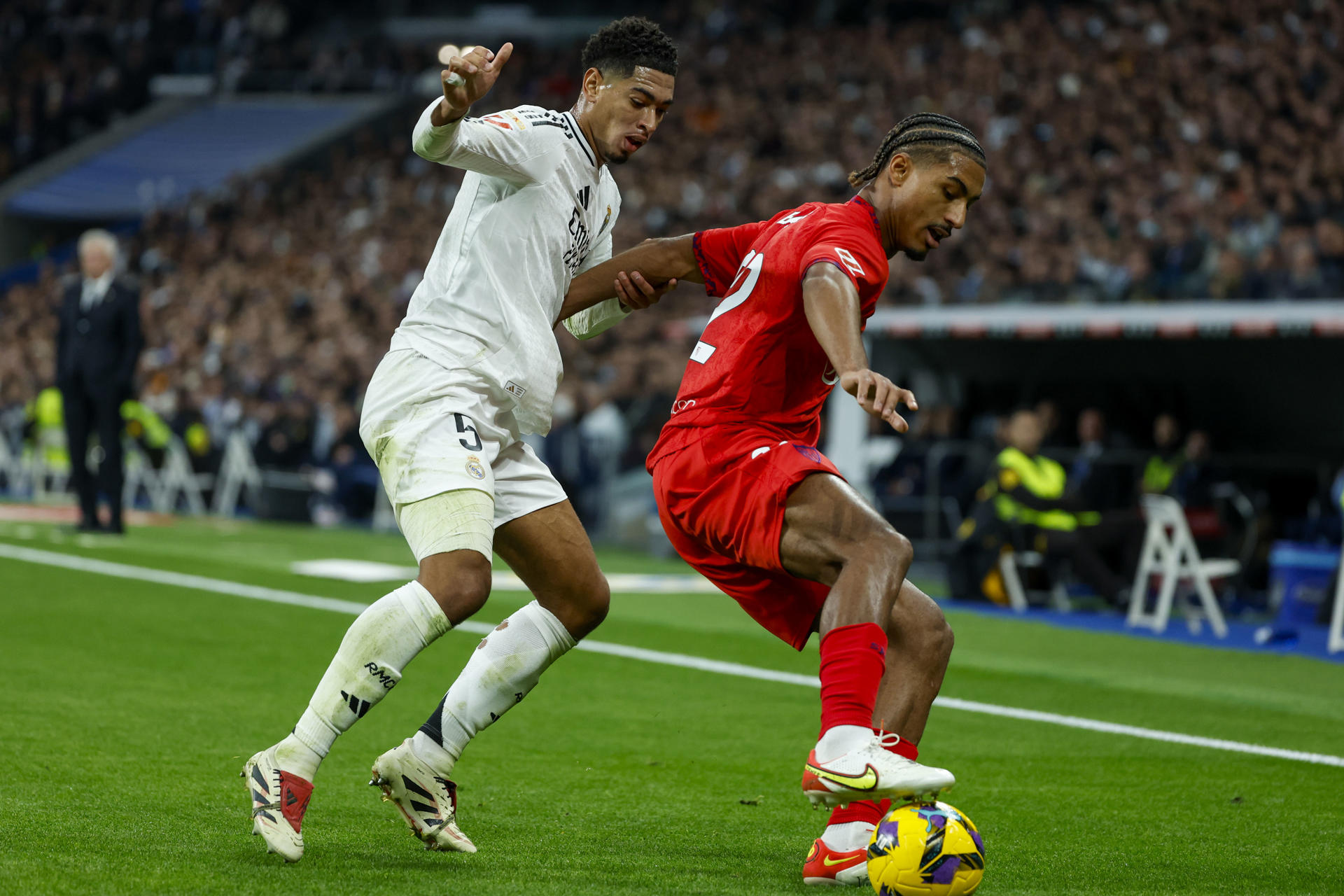 El centrocampista inglés del Real Madrid Jude Bellingham (i) y el defensa francés del Sevilla Loic Bade durante el partido de LaLiga entre el Real Madrid y el Sevilla el 22 de diciembre de 2024. EFE/ JuanJo Martín
