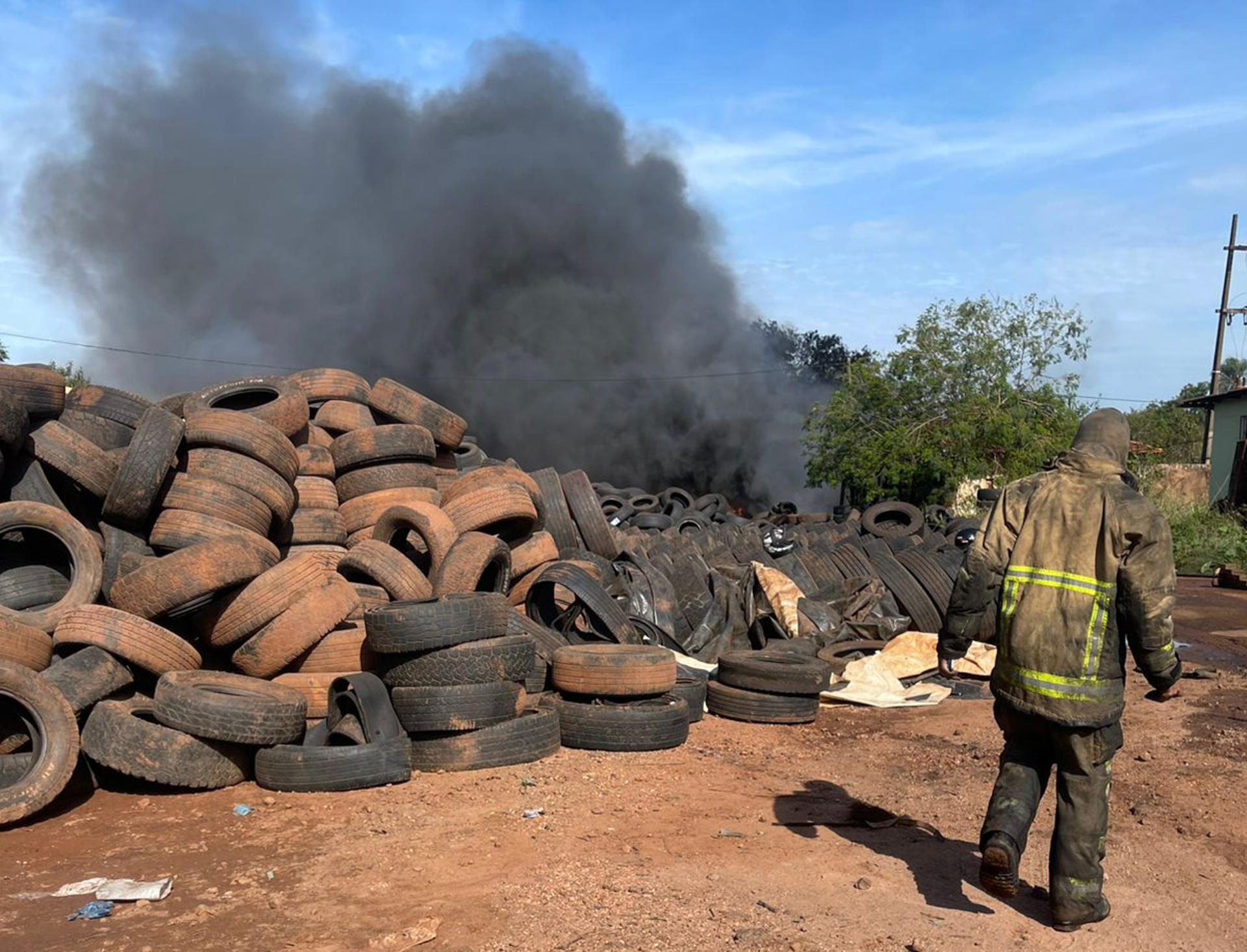 Fotografía cedida por el Cuerpo de Bomberos Voluntarios de Paraguay de un bombero caminado al lado de un incendio en una bodega de almacenamiento de neumáticos este domingo, en la ciudad de Pedro Juan Caballero (Paraguay). EFE/ Cuerpo de Bomberos Voluntarios de Paraguay