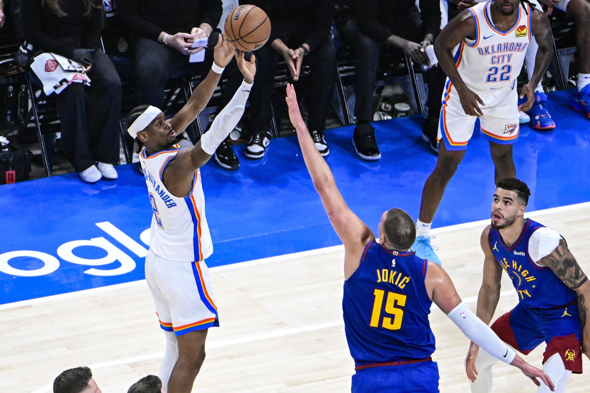 El escolta de los Oklahoma City Thunder, Shai Gilgeous-Alexander (I) lanza a canasta ante el pívot de los Denver Nuggets Nikola Jokic (C), en el quinto partido de las semifinales de la Conferencia Oeste de la NBA. EFE/EPA/GERALD LEONG SHUTTERSTOCK OUT