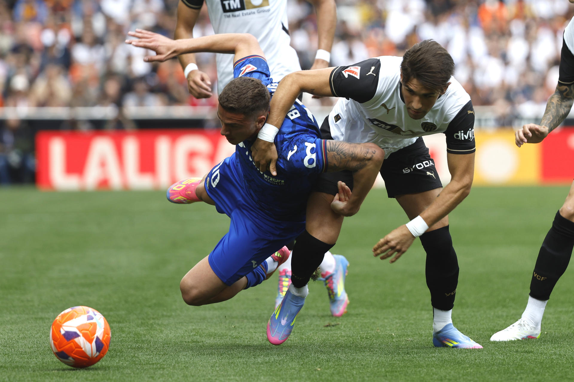 El delantero del Getafe Bertug Ozgur Yildirim (i) y el defensa del Valencia Jesús Vázquez, durante el partido de la jornada 35 de LaLiga EA Sports disputado este sábado en el Estadio de Mestalla en Valencia. EFE/Ana Escobar