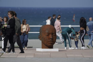 Viandantes por el paseo del muro de San Lorenzo ante una escultura de Samuel Salcedo este fin de semana. EFE/Paco Paredes