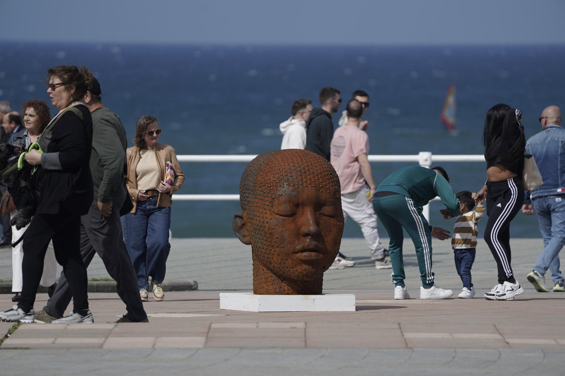 Viandantes por el paseo del muro de San Lorenzo ante una escultura de Samuel Salcedo este fin de semana. EFE/Paco Paredes