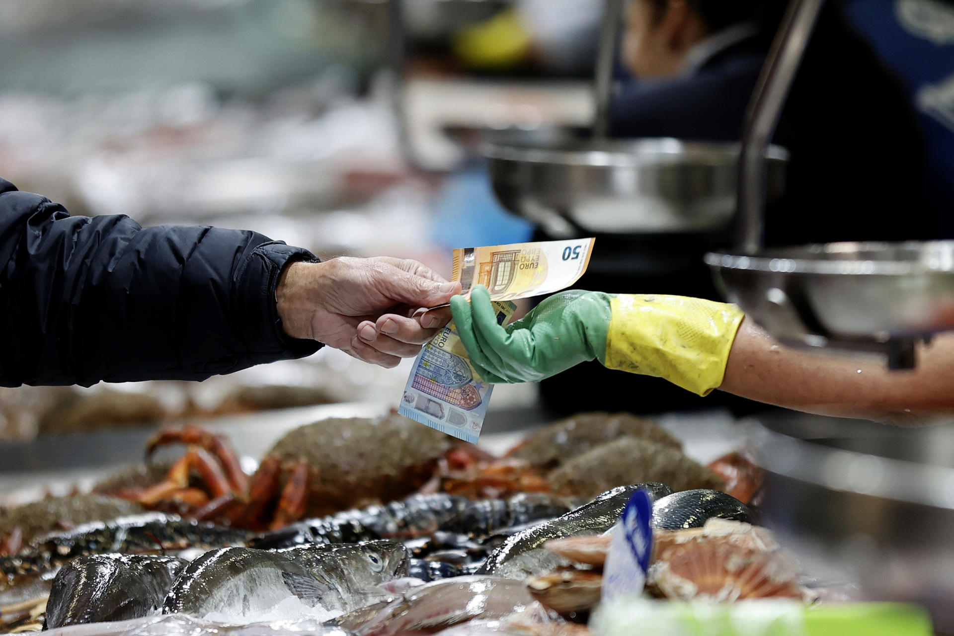 Un hombre paga el pescado adquirido en uno de los puestos del mercado de la plaza de Lugo, en la ciudad de A Coruña. EFE/Cabalar