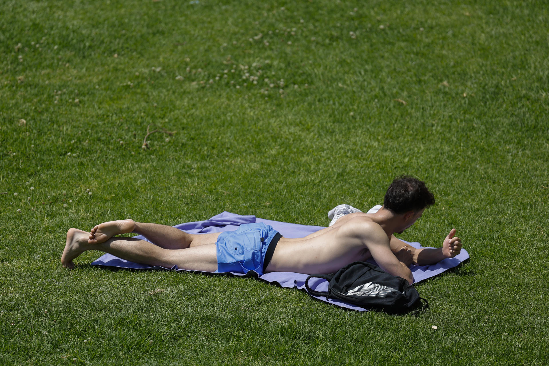 Una persona toma el sol en los jardines del antiguo cauce del Turia durante este lunes en el que se viven ya temperaturas veraniegas. EFE/Ana Escobar