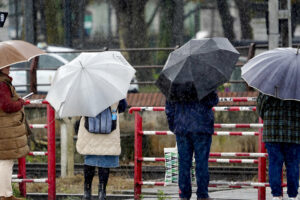Viandantes esperan un paso a nivel bajo una intensa lluvia en Avilés (Asturias), en una fotografía de archivo. EFE/Paco Paredes