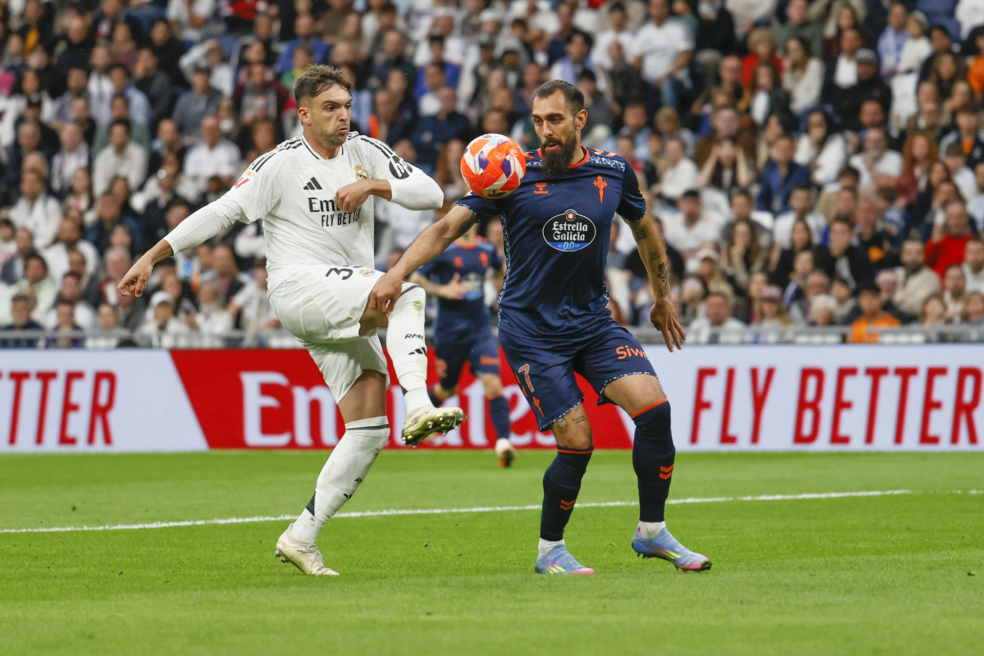 El defensa del Real Madrid Raúl Asencio (i) lucha por el balón con el delantero del Celta de Vigo Borja Iglesias durante el partido entre el Real Madrid y el Celta de Vigo este domingo en el estadio Santiago Bernabéu en Madrid este domingo. EFE/ Blanca Míllez