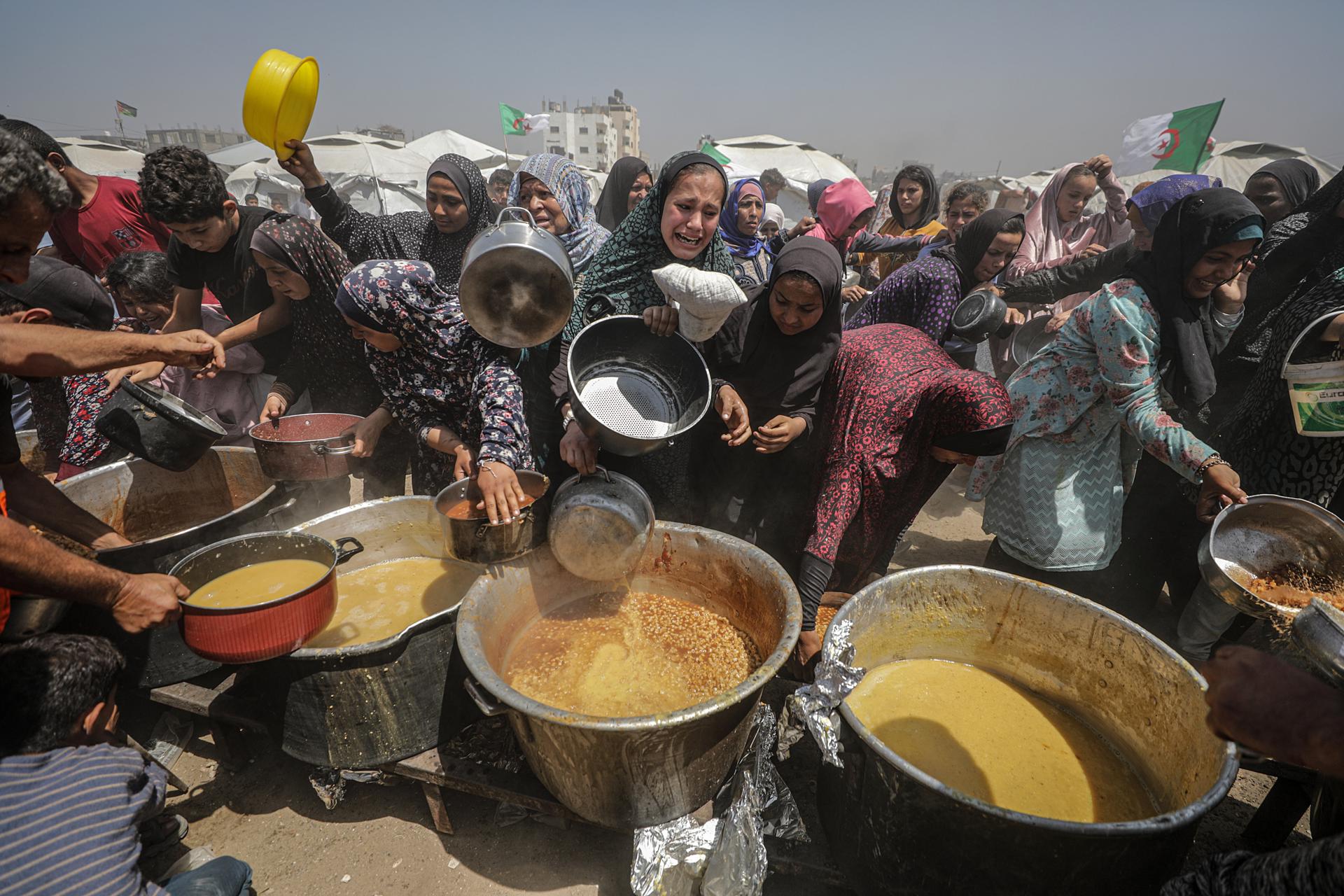 Palestinos desplazados internos se reúnen para recibir una porción de comida de una cocina benéfica, en el campo de refugiados de Jabalia, en el norte de la Franja de Gaza, el 09 de mayo de 2025. Según la agencia de la ONU para los refugiados palestinos UNRWA, más de un millón de personas en la Franja de Gaza están experimentando 'altos niveles' de inseguridad alimentaria aguda, con una malnutrición aguda varias veces superior a la anterior a la guerra. La ONU estima que al menos 1,9 millones de personas (nueve de cada diez) están desplazadas internamente. EFE/EPA/MOHAMMED SABER