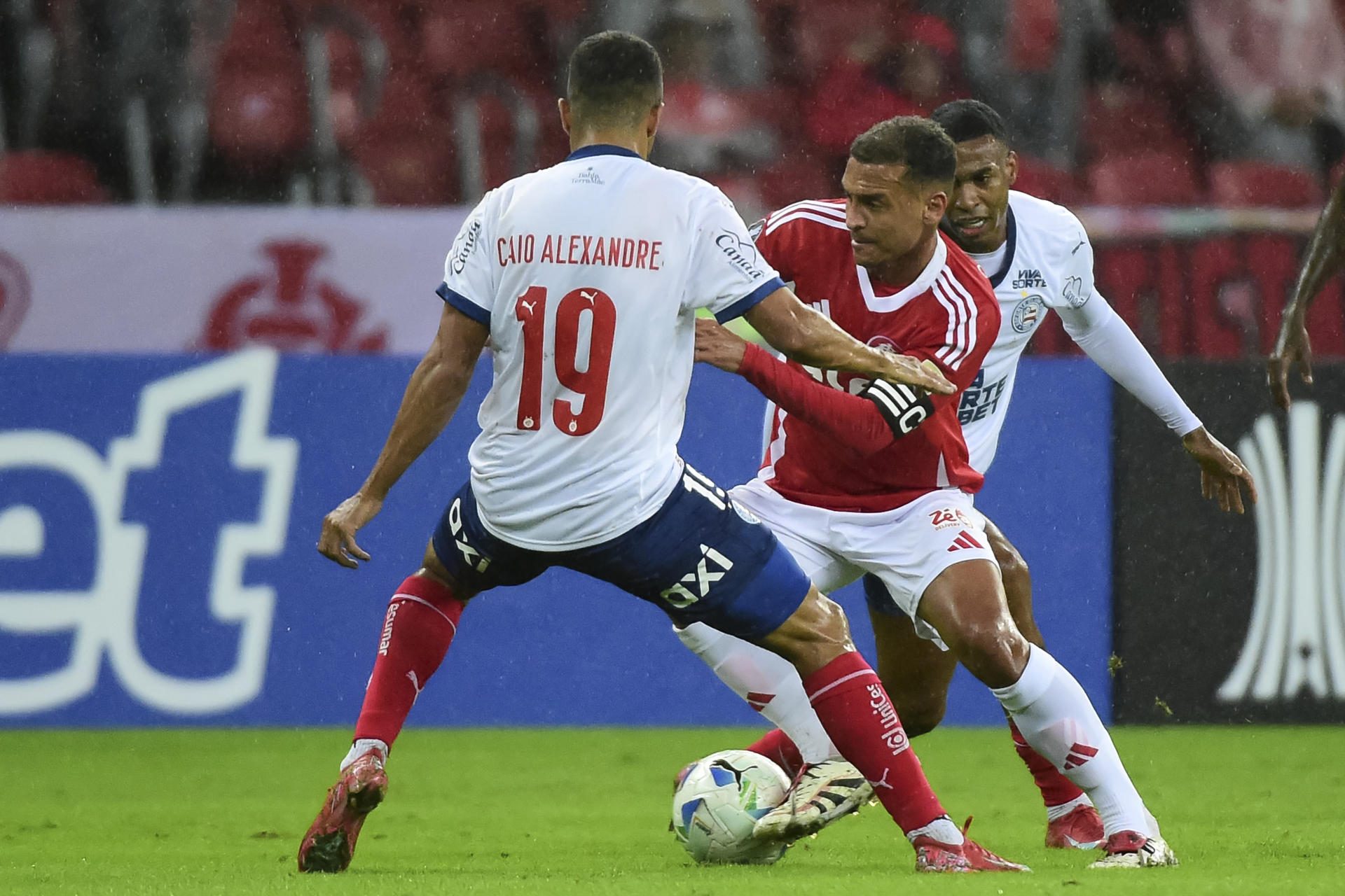 Alan Patrick (c) de Internacional disputa un balón con Caio Alexandre de Bahia en la Copa Libertadores. EFE/Ricardo Rimoli