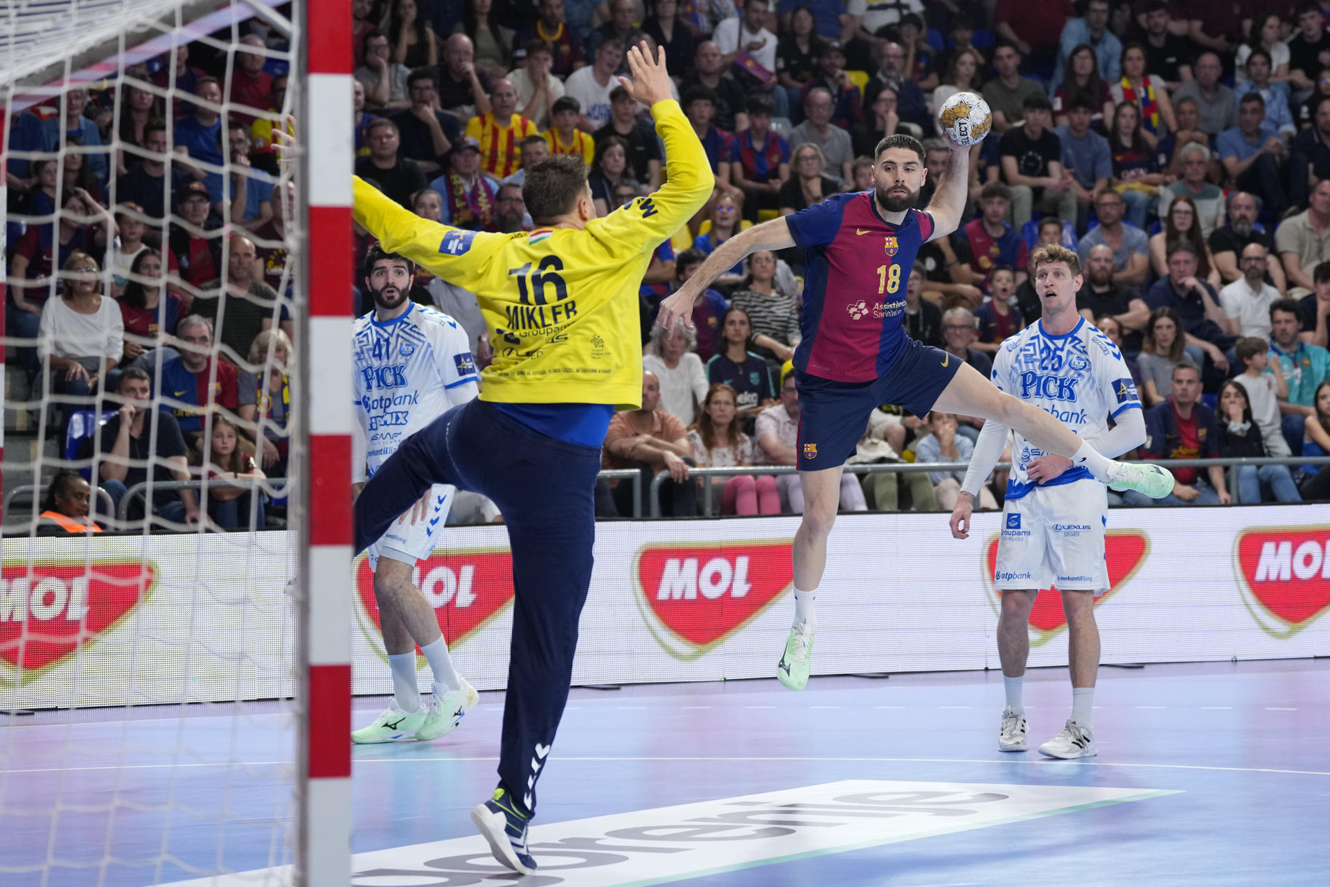 El jugador del FC Barcelona, Janc (d), se dispone a lanzar ante el portero del OTP Bank Pick Szeged durante el encuentro de vuelta de los play off de la EHF que disputan hoy jueves FC Barcelona y OTP Bank Pick Szeged en el Palau Blaugrana, en Barcelona. EFE / Alejandro García.