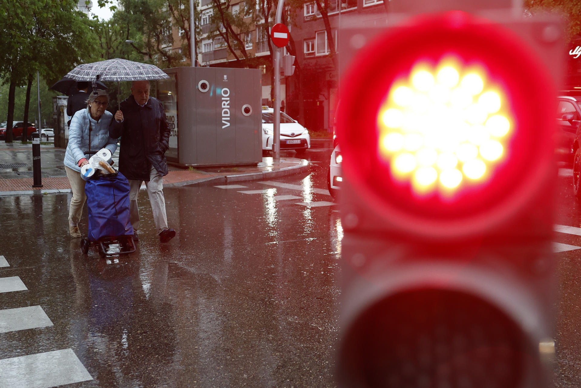 Varias personas se protegen de la lluvia caída este lunes en Madrid. EFE/ Mariscal