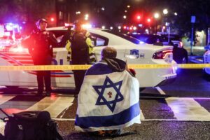 Un hombre con una bandera israelí este jueves en el lugar donde fueron asesinadas dos personas que trabajaban en la embajada de Israel en Washington. EFE/EPA/WILL OLIVER