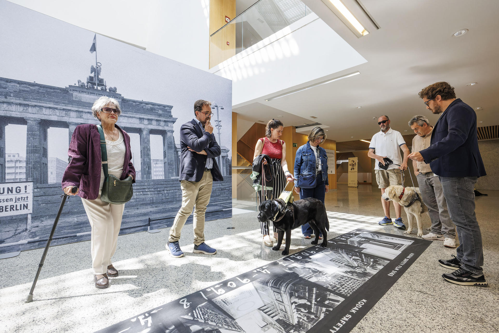 El comisario de la exposición 'Tu memoria colectiva', Javier Marín (d), guía a una delegación de la ONCE por la exposición fotográfica expuesta en Burgos, este martes. Una delegación de la ONCE ha visitado este martes 'Tu memoria colectiva', la exposición fotográfica que la Agencia EFE muestra en el Fórum Evolución de Burgos y que cuenta con un espacio inclusivo que también permite a las personas con diversidad visual disfrutar de imágenes emblemáticas de la historia universal reciente a través del tacto. EFE/ Roman G. Aguilera