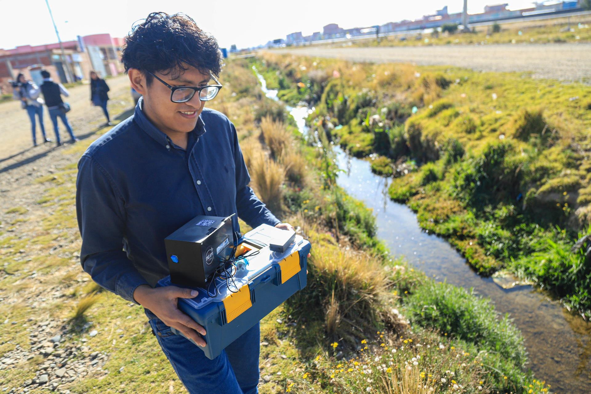 El estudiante José Felix Sarmiento prueba un dispositivo diseñado para medir de forma rápida y precisa los niveles de contaminación en el agua este miércoles, en Viacha (Bolívia). EFE/ Gabriel Márquez