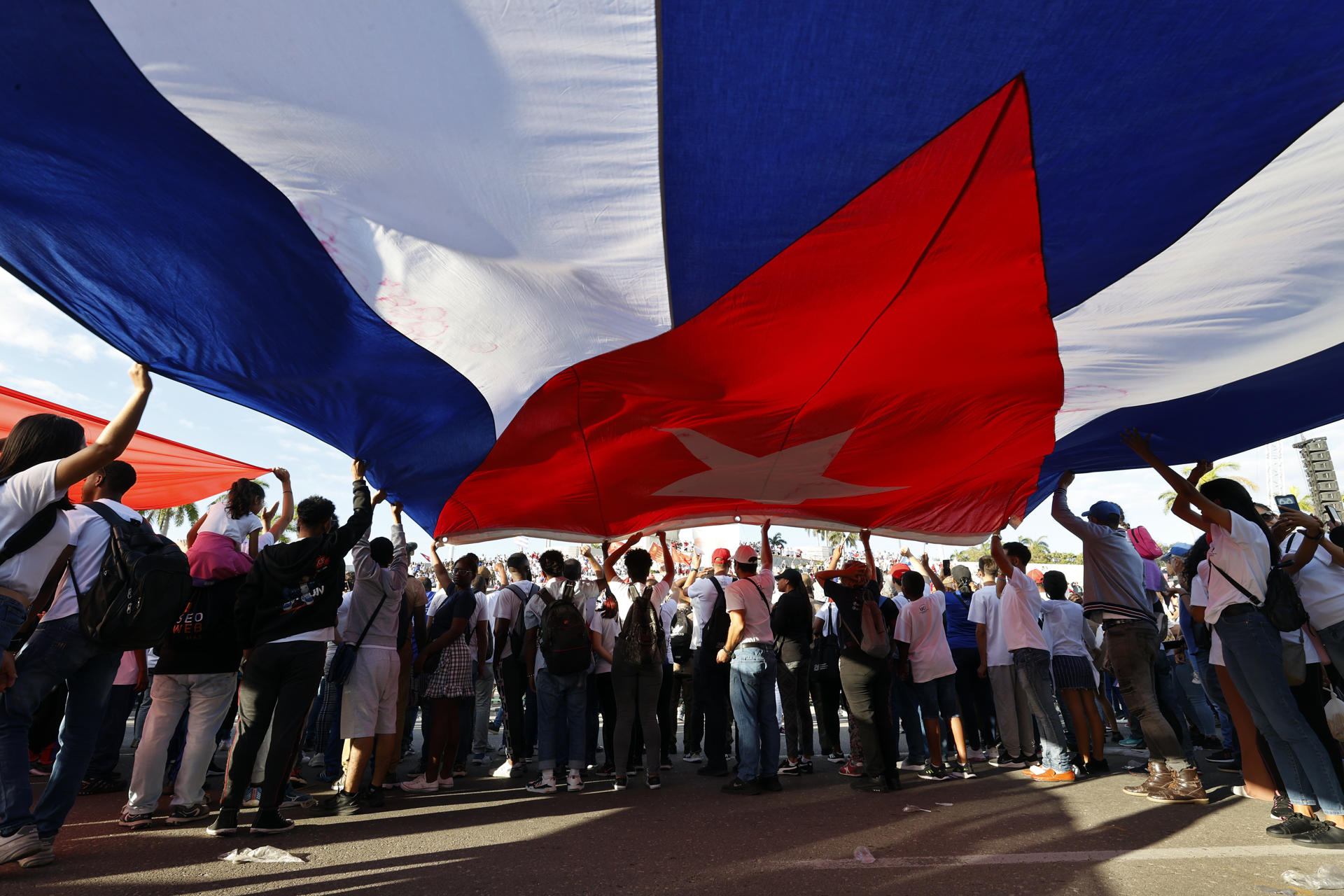 Personas sostienen una bandera de Cuba durante el desfile del Primero de Mayo este jueves, en la Habana (Cuba). EFE/ Ernesto Mastrascusa