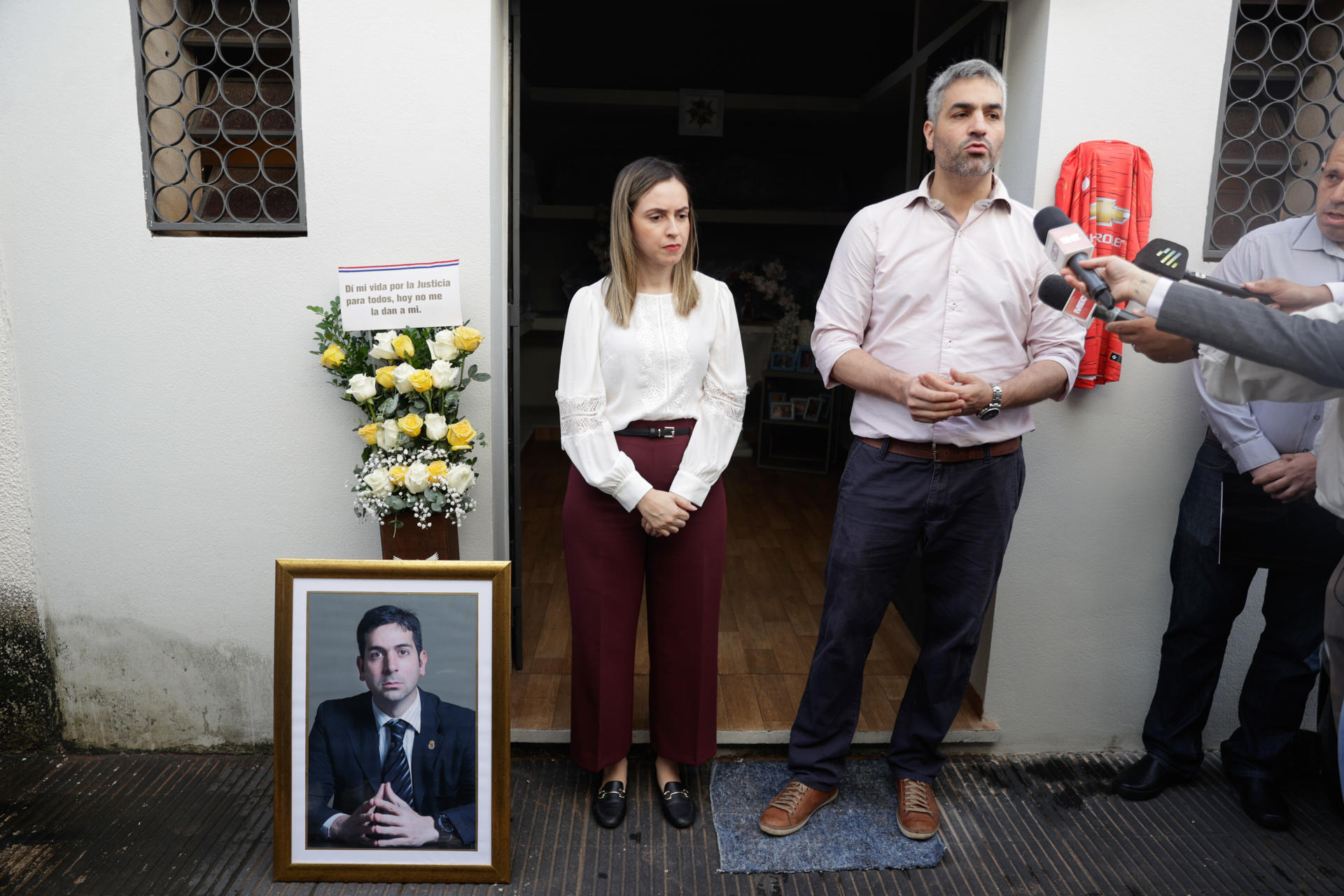 El hermano del fiscal paraguayo Marcelo Pecci, Francisco Pecci (d), habla con la prensa junto a la esposa del fiscal, Claudia Aguilera durante un homenaje a tres años del homicidio del fiscal, este sábado en el cementerio la Recoleta en Asunción (Paraguay). EFE/ Juan Pablo Pino