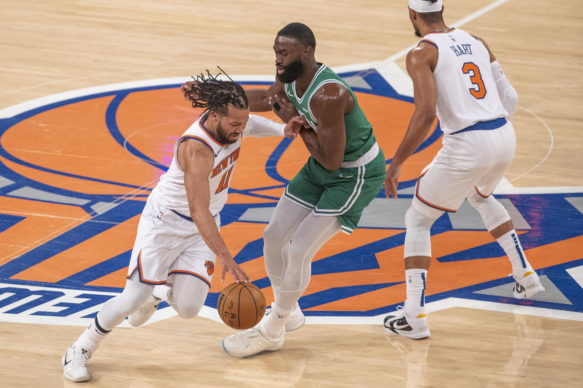 Jalen Brunson (i) de los Knicks busca huir de la marca de Jaylen Brown (c) de los Celtics este viernes durante el partido que ganaron con amplitud los de Nueva York por 119-81 en el Madison Square Garden y que les garantizó el pase a su primera final de la Conferencia Este en 25 años. . EFE/ Ángel Colmenares