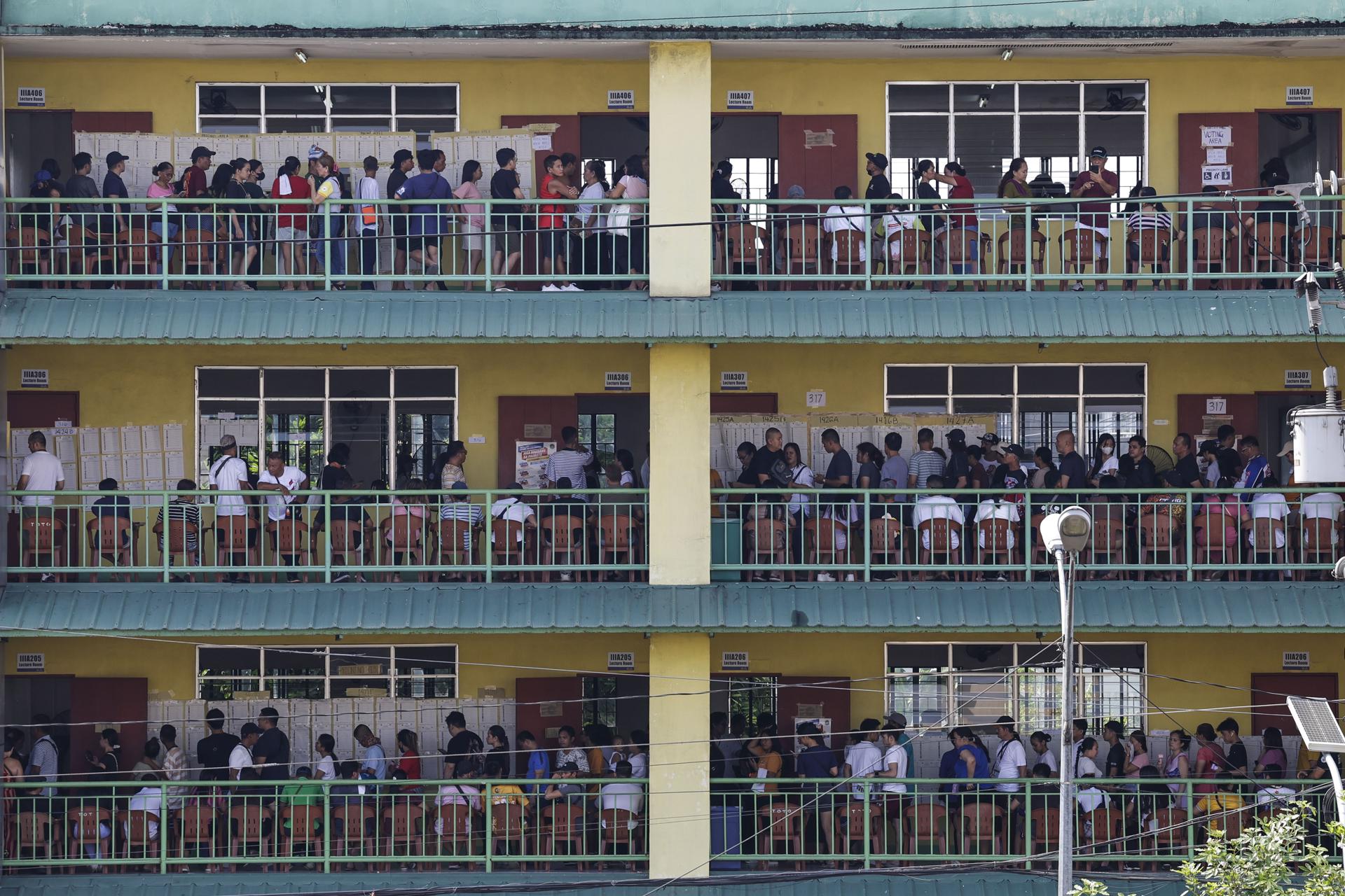 Filipinos se dirigen a las aulas para votar en una escuela utilizada como centro de votación en Ciudad Quezón, Gran Manila, Filipinas, este lunes. Se espera que unos 68 millones de ciudadanos emitan su voto durante las elecciones intermedias nacionales y locales del 12 de mayo, en las que se espera cubrir aproximadamente 18.000 puestos gubernamentales, desde senadores hasta funcionarios locales. EFE/ Rolex Dela Pena