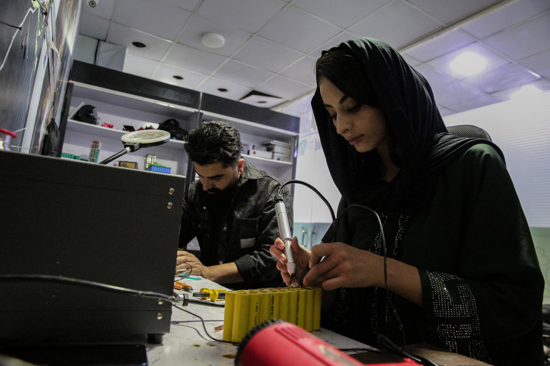 Zahra Ali (D), una niña afgana, ensambla baterías externas en su taller en Kabul, Afganistán, 30 de abril de 2025. Zahra Ali, una innovadora de 23 años en Kabul, dirige un equipo que produce baterías de litio caseras, proporcionando electricidad muy necesaria a los hogares en las regiones desatendidas de Afganistán. Cada batería, que varía de uno a cinco kilovatios, se fabrica utilizando piezas recicladas de automóviles Tesla procedentes de Dubái, y cada placa podría valer 24.000 USD en el mercado comercial. El taller de Zahra produce actualmente tres baterías diarias, pero lucha por satisfacer la creciente demanda, generando entre 2.000 y 5.000 dólares mensuales, que se reinvierten en la adquisición de más materiales. Ella enfatiza el impacto de su trabajo, afirmando que "las baterías que produzco pueden alimentar equipos de producción; con este trabajo, estoy tratando de guiar a las mujeres afganas hacia la autosuficiencia". A pesar de los desafíos, Zahra tiene como objetivo inspirar a más mujeres a ingresar al campo de la tecnología y planea lanzar clases de robótica para niñas en el futuro. (Afganistán) EFE/EPA/SAMIULLAH POPAL