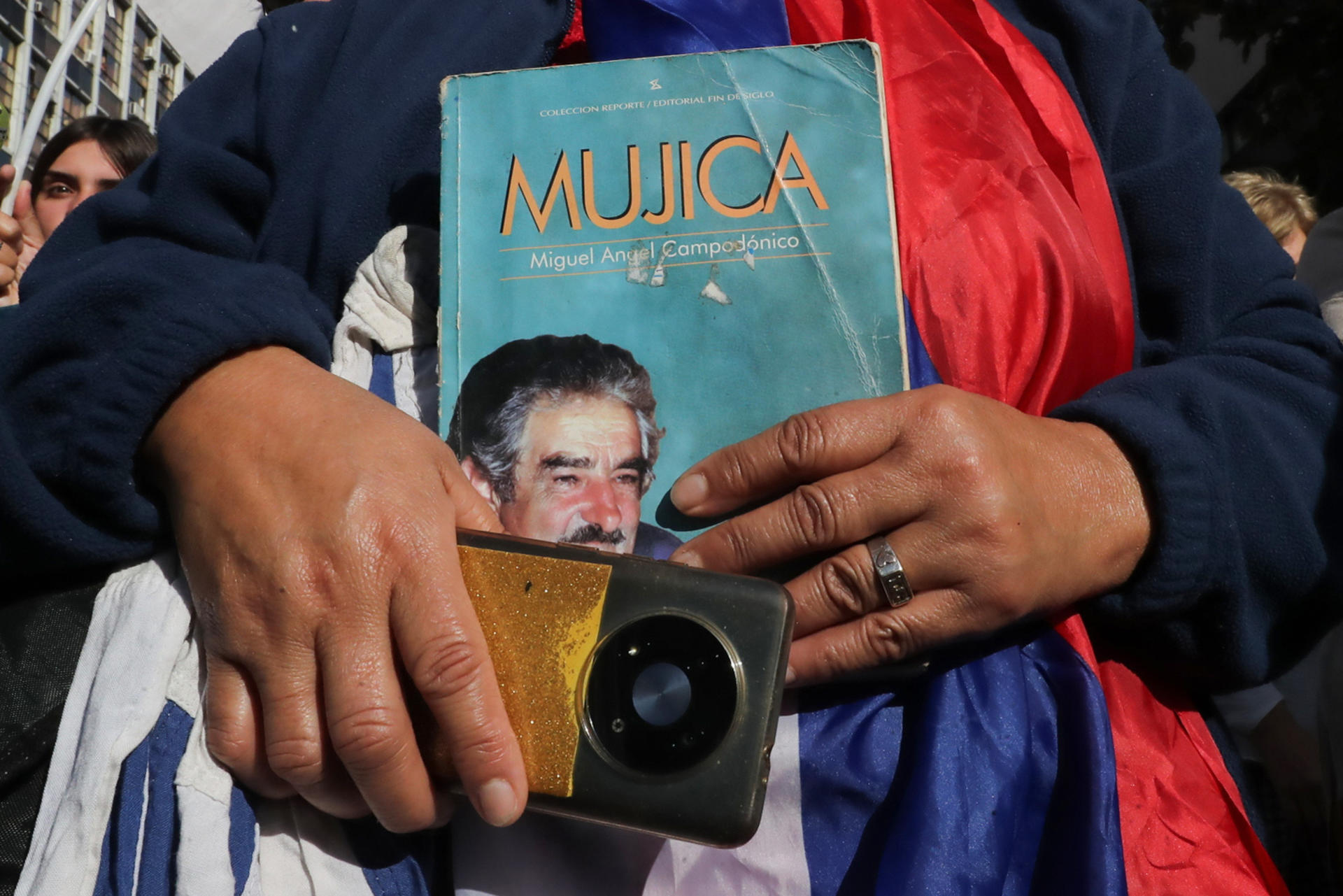 Una persona sostiene un libro durante el cortejo fúnebre del expresidente uruguayo José Mujica este 14 de mayo de 2025, en Montevideo (Uruguay). EFE/ Raúl Martínez