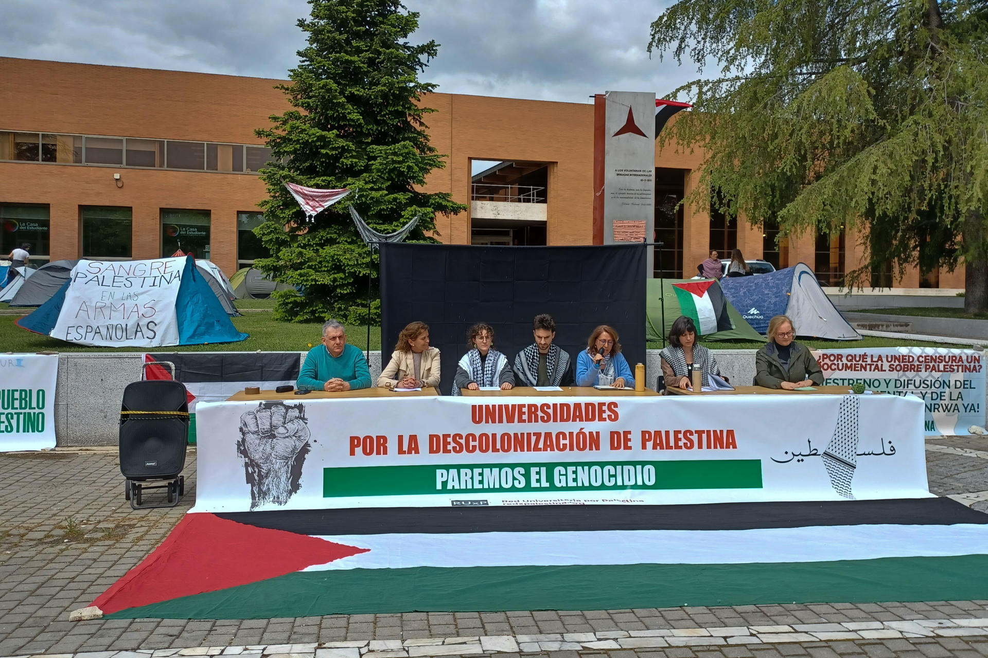 MADRID, 14/05/2025.- Los miembros de la Red Universitaria por Palestina (RUxP) de Madrid, ante la "inacción y el silencio cómplice de las instituciones", han retomado la acampada en la explanada de la Ciudad Universitaria, donde han anunciado la creación de un 'Tribunal de los Pueblos sobre Gaza' que se reunirá en octubre próximo. Así lo han anunciado profesores y estudiantes de la Red en una rueda de prensa frente a una veintena de tiendas de campaña instaladas desde ayer martes, y ante una gran pancarta con los lemas 'Universidades por la desconolización de Palestina. Paremos el genocidio' o'Sangre palestina en las armas españolas'.EFE/Juliana Leao-Coelho Rego