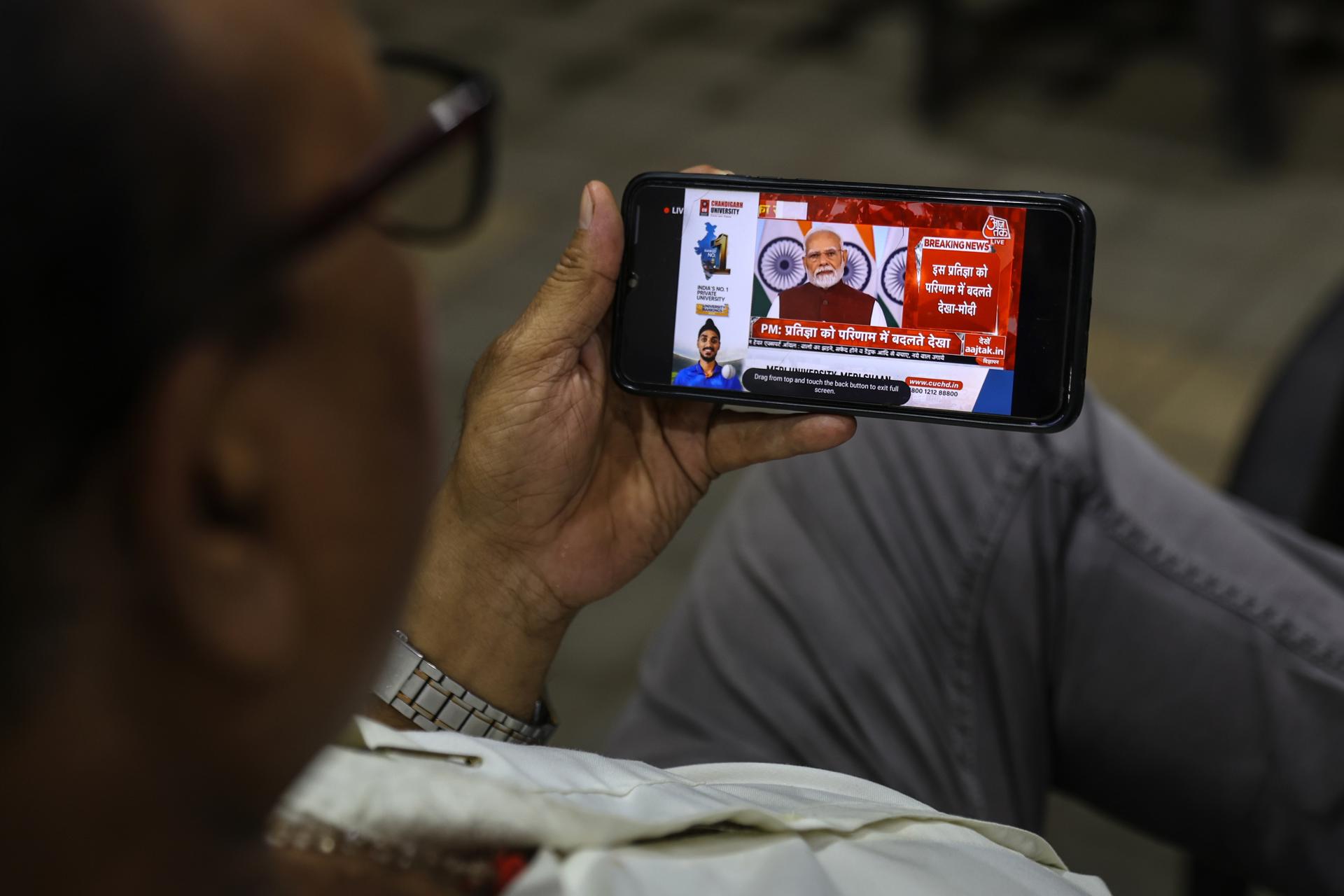 Un hombre observa una retransmisión en directo por televisión del Primer Ministro indio, Narendra Modi, dirigiéndose a la nación por primera vez desde las recientes escaladas en el conflicto entre India y Pakistán, en su teléfono móvil en Mumbai, India, el 12 de mayo de 2025. El 10 de mayo de 2025 entró en vigor un alto el fuego entre Pakistán y la India, tras días de escalada militar. EFE/EPA/DIVYAKANT SOLANKI