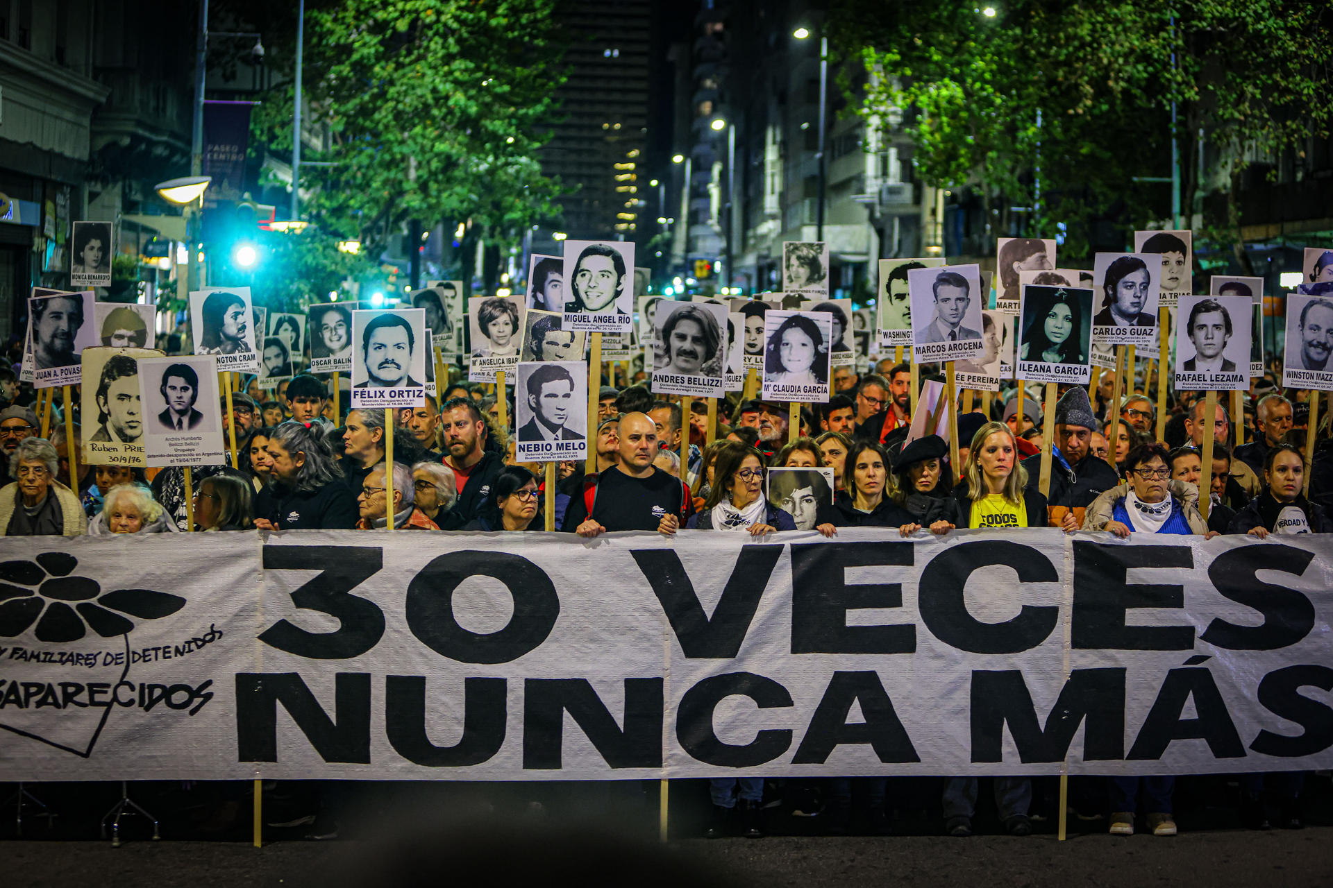 Personas sostienen imágenes de personas desaparecidas durante la trigésima edición de la Marcha del Silencio este martes, en Montevideo (Uruguay). EFE/ Gaston Britos