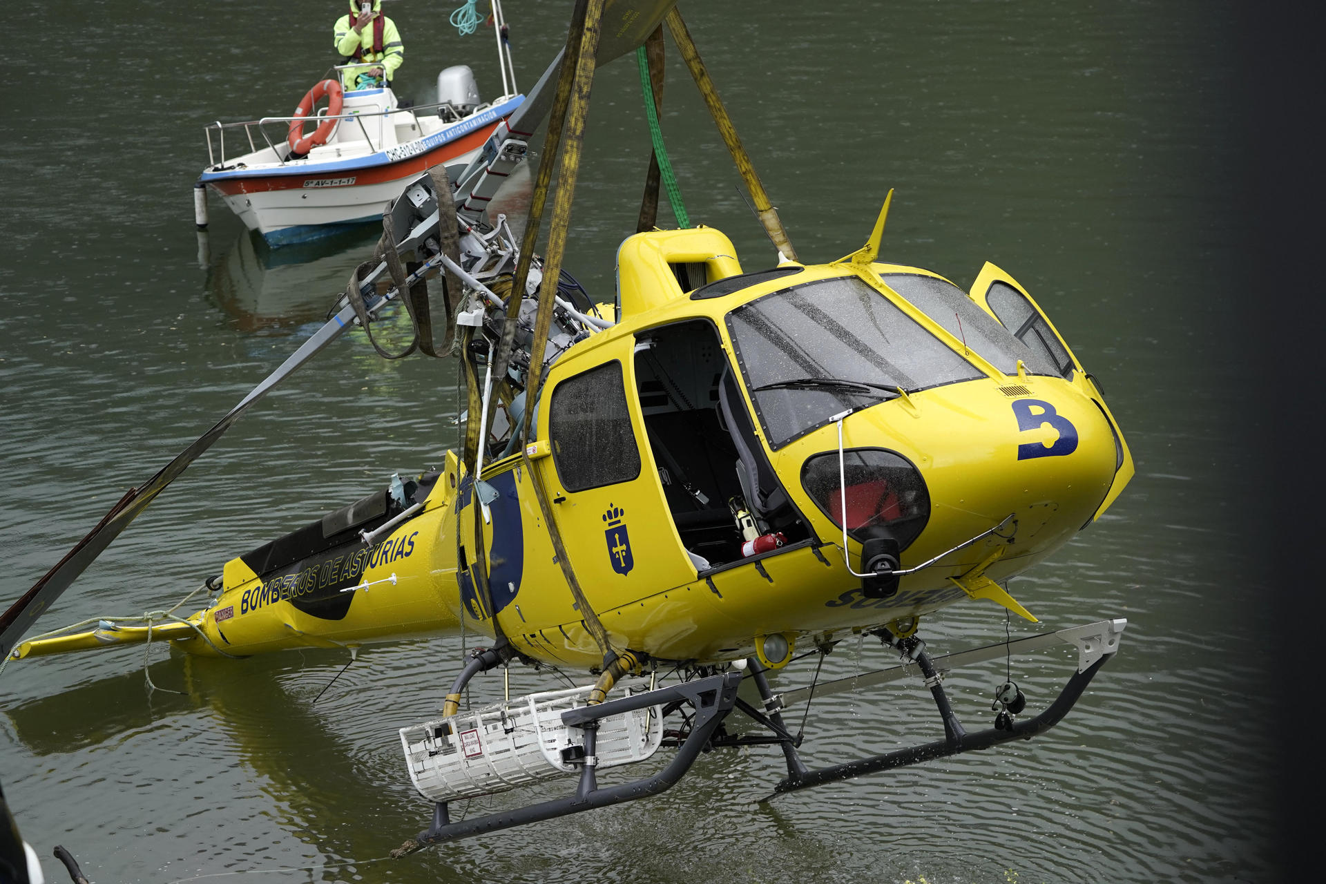Un equipo de buzos se ha encargado de reflotar este domingo el helicóptero de Bomberos de Asturias que el viernes se precipitó al embalse de Tanes al tropezar con un tendido eléctrico la estructura que llevaba colgada para sacar agua destinada a las tareas de extinción de un incendio forestal cercano. El helicóptero se encontraba boca abajo a diez metros de profundidad en la cabecera de este embalse, destinado al abastecimiento de agua potable a cientos de miles de personas del área central de Asturias. EFE/ Paco Paredes