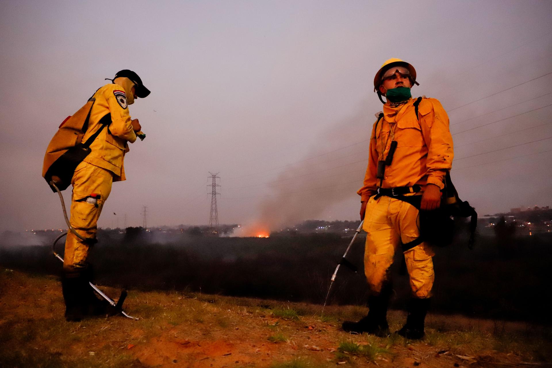 Fotografía de archivo que muestra a bomberos paraguayos que descansan por un momento durante su lucha contra un incendio en la Costanera, en Asunción (Paraguay). EFE/Nathalia Aguilar