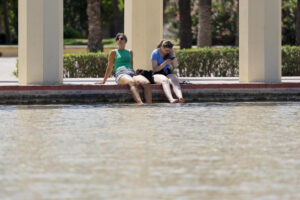 Dos personas se refrescan en una fuente de los jardines del antiguo cauce del Turia para combatir el calor que vive durante este lunes. EFE/Ana Escobar