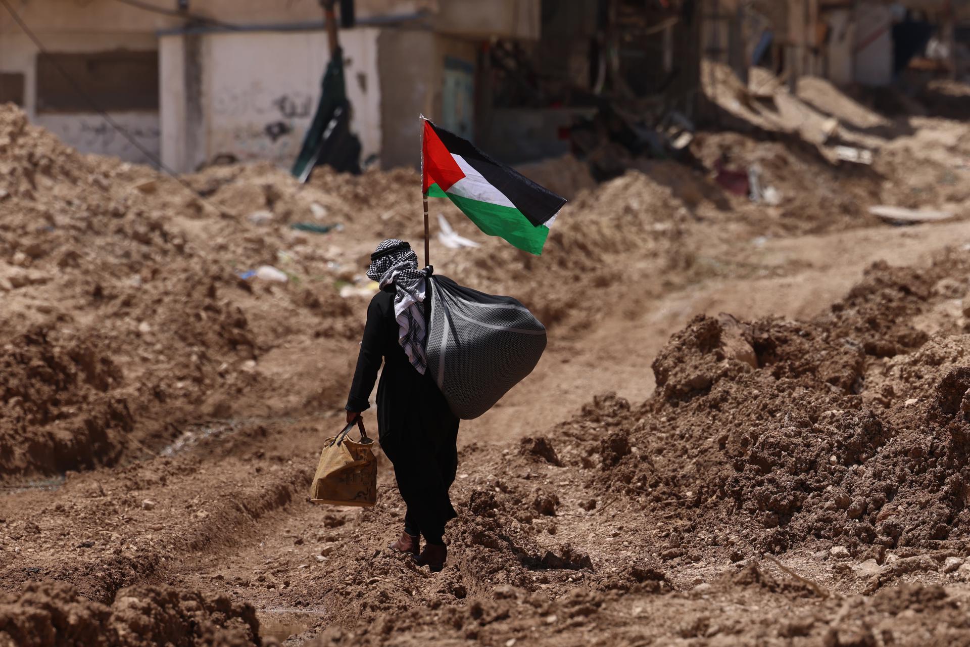 Fotografía de un hombre palestino que camina frente a la entrada principal del campo de refugiados de Tulkarem en la ciudad cisjordana de Tulkarem, el 19 de mayo de 2025. EFE/EPA/ALAA BADARNEH