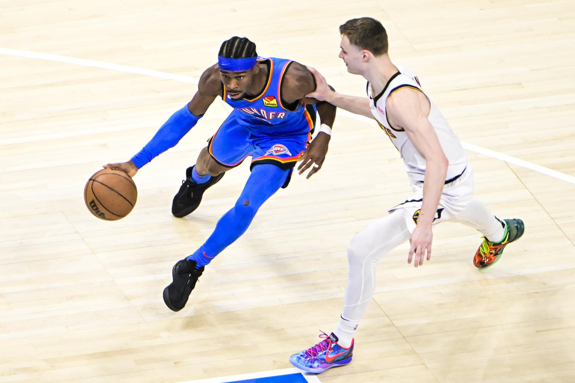 Shai Gilgeous-Alexander (i) de los Oklahoma City Thunder en acción ante la marca de Christian Braun de los Denver Nuggets. EFE/GERALD LEONG