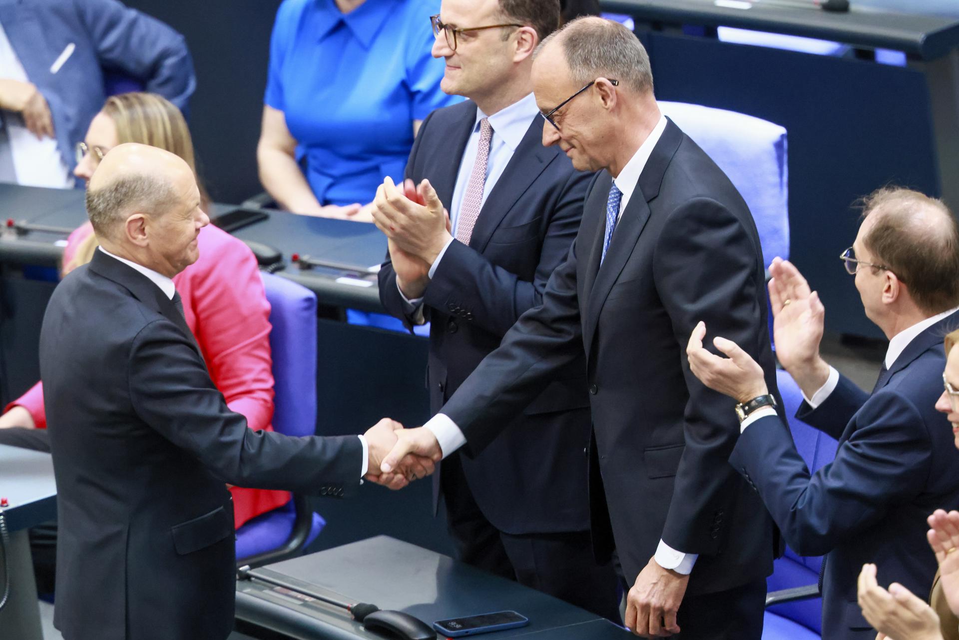 El canciller alemán saliente Olaf Scholz (I) felicita al recién elegido canciller Friedrich Merz (C) tras la segunda ronda de votación en el Bundestag en Berlín, Alemania, 06 de mayo de 2025. Se espera que el nuevo gobierno alemán se forme entre los partidos de la Unión de la Unión Demócrata Cristiana (CDU) y la Unión Social Cristiana (CSU) y el socio de coalición el Partido Socialdemócrata (SPD). (Alemania) EFE/EPA/HANNIBAL HANSCHKE