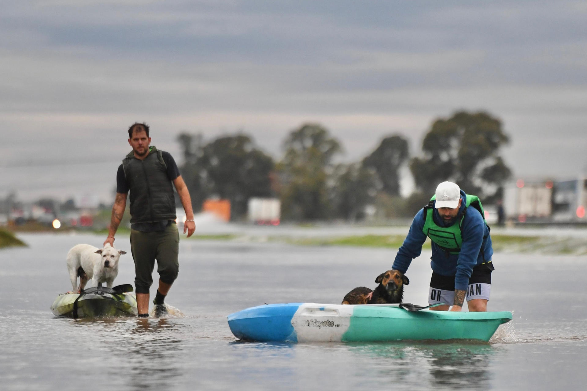 Dos hombres transportan a unos perros en unos kayaks a través de una calle inundada este sábado, en Campana, Buenos Aires (Argentina). EFE/ STR