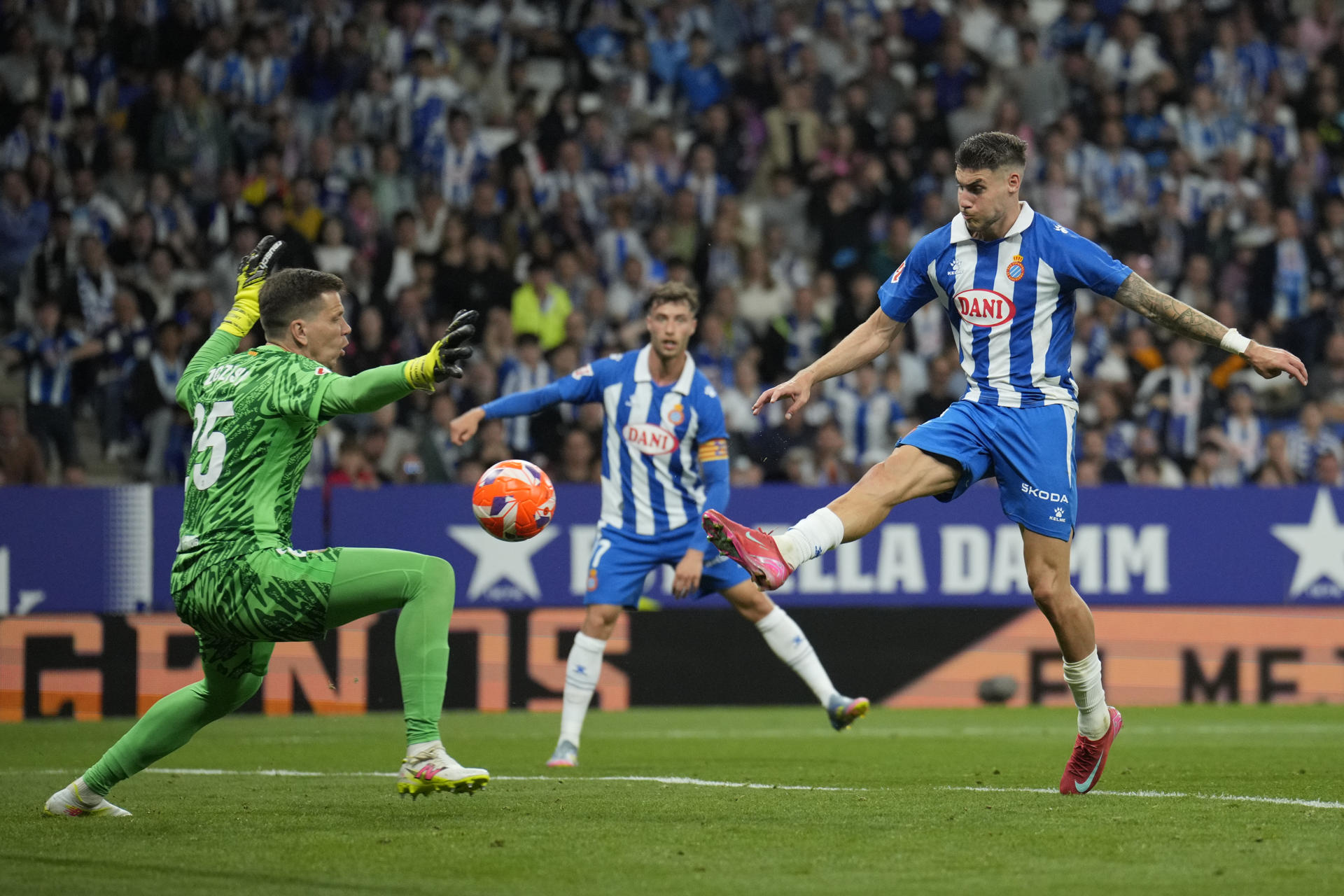 El delantero del Espanyol Roberto Fernández (d) remata ante Wojciech Szczesny, guardameta del FC Barcelona, durante el encuentro correspondiente a la jornada 36 de LaLiga EA Sports que RCD Espanyol y FC Barcelona disputaron en el RCDE Stadium, en Cornellá de Llobregat, Barcelona. EFE/Alejandro García