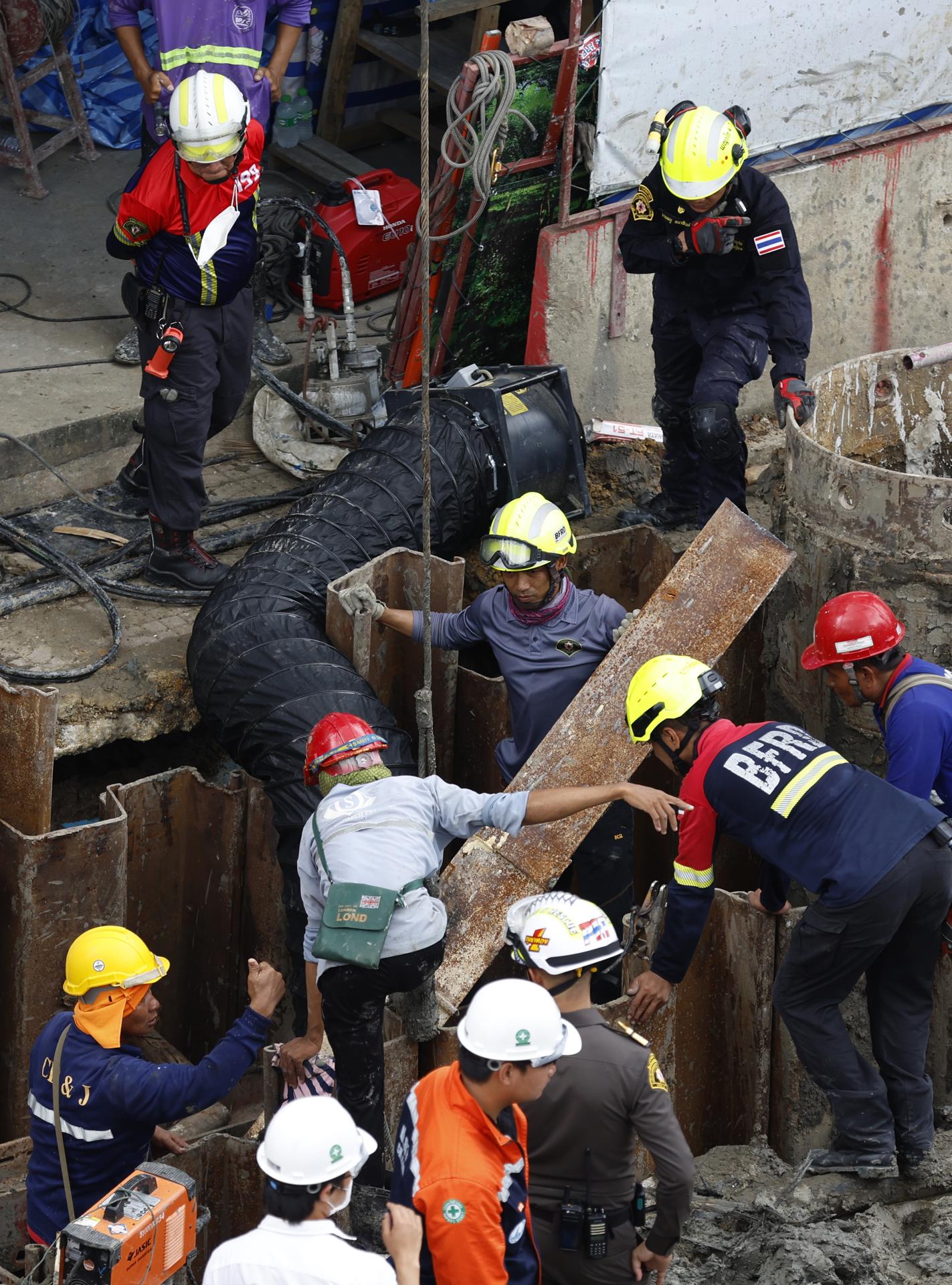 Rescatistas y obreros participan en una operación para rescatar a un trabajador que cayó en un socavón de 19 metros de profundidad en una obra de metro en Bangkok. EFE/EPA/NARONG SANGNAK