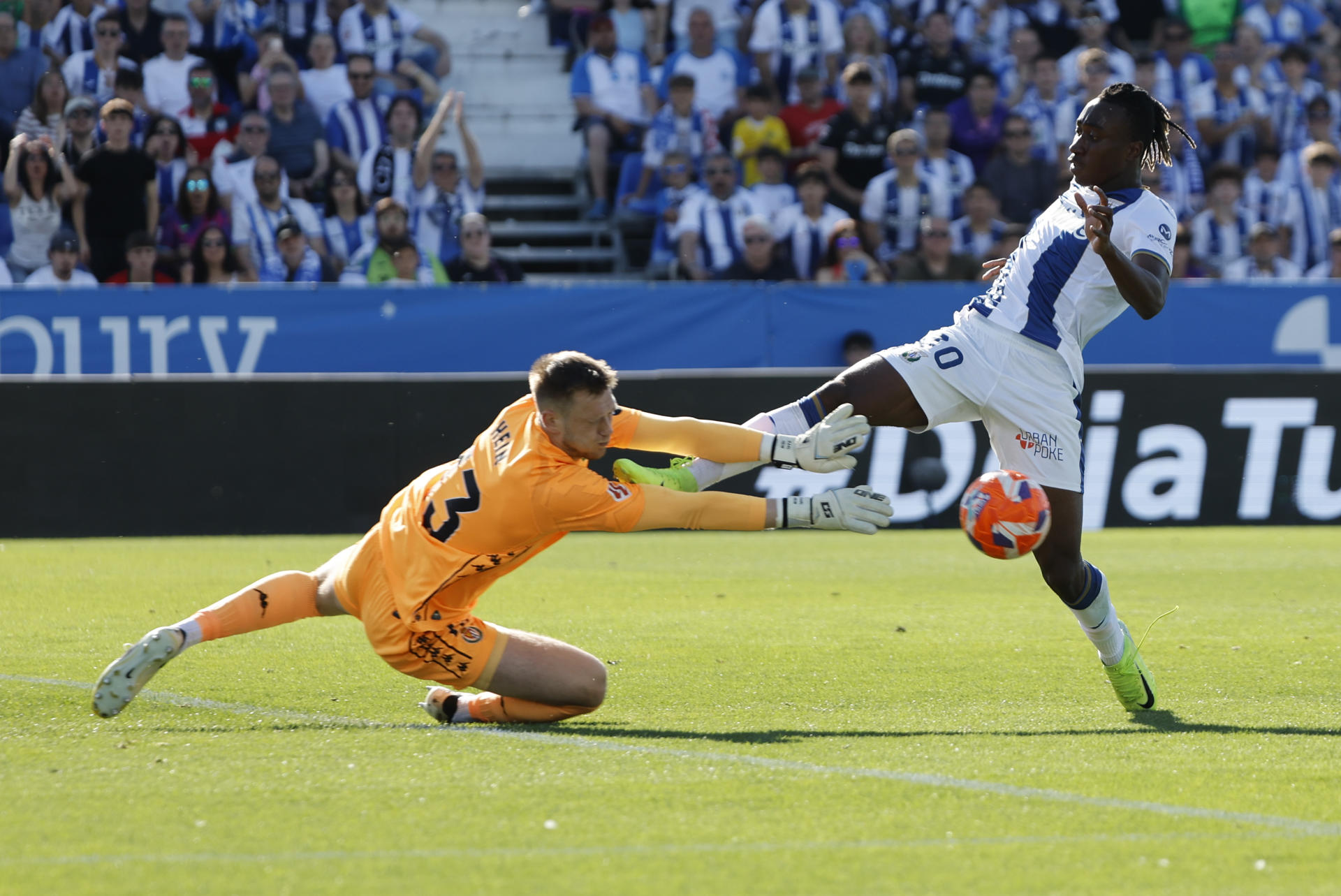 El delantero del Leganés Yan Diomande (d) trata de superar al portero Marko Dmitrovic, del Valladolid, durante el partido de LaLiga de fútbol que CD Leganés y Real Valladolid disputan este sábado en el estadio de Butarque. EFE/Sergio Pérez
