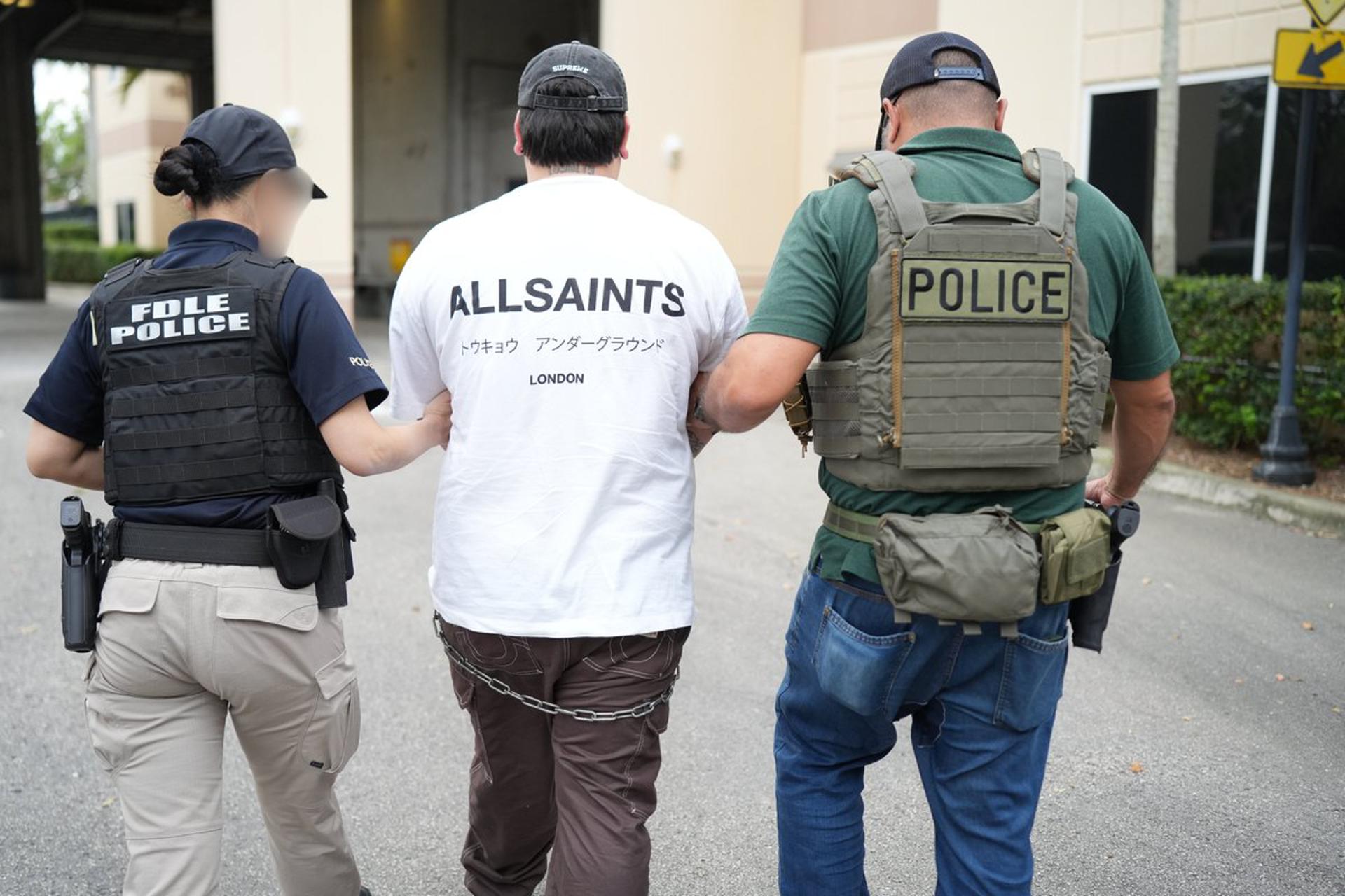 Fotografía cedida por el Departamento de Aplicación de la Ley de Florida (FDLE) de agentes de la policía trasladando a un inmigrante detenido durante la operación 'Marea Negra' este jueves, en Miami (Estados Unidos). EFE/ Departamento de Aplicación de la Ley de Florida /