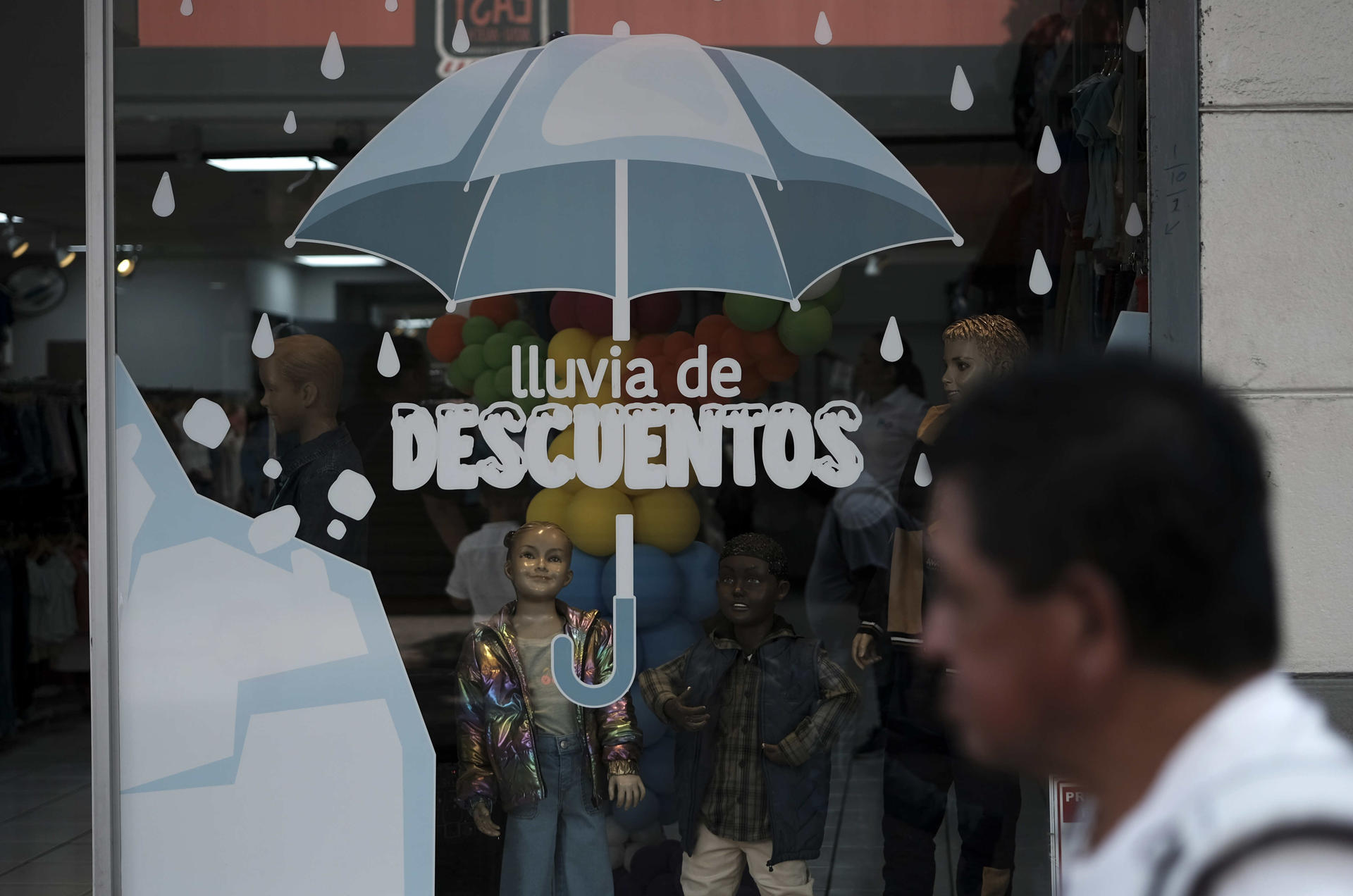 Fotografía de archivo de un hombre al caminar junto a una vitrina de local comercial en San José (Costa Rica). EFE/Jeffrey Arguedas