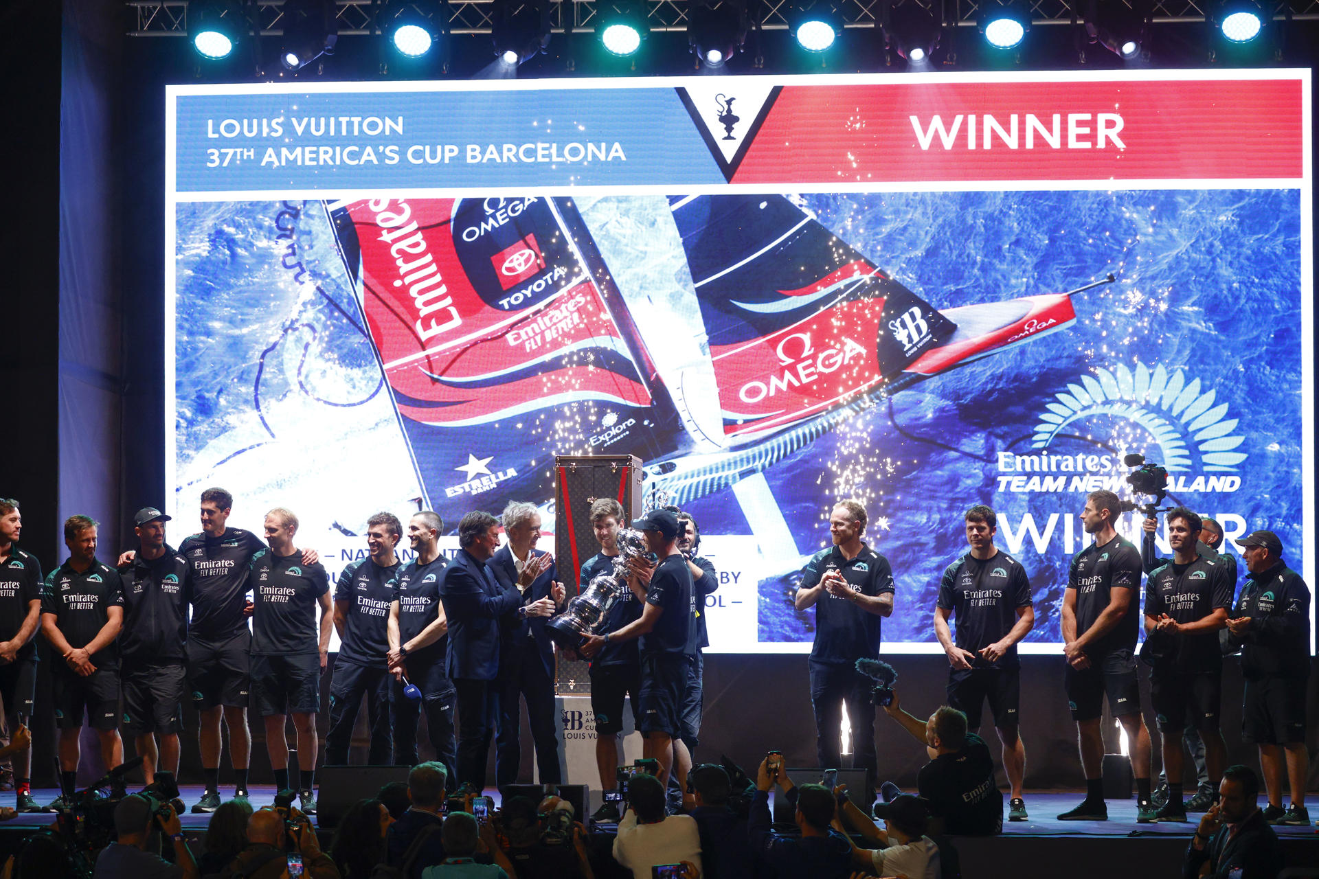 El timonel del Emirates Team New Zealand, Peter Burling (c), levanta el trofeo de la 37 edición de la Copa del América, el 19 de octubre de 2024, en Barcelona. EFE/ Quique García