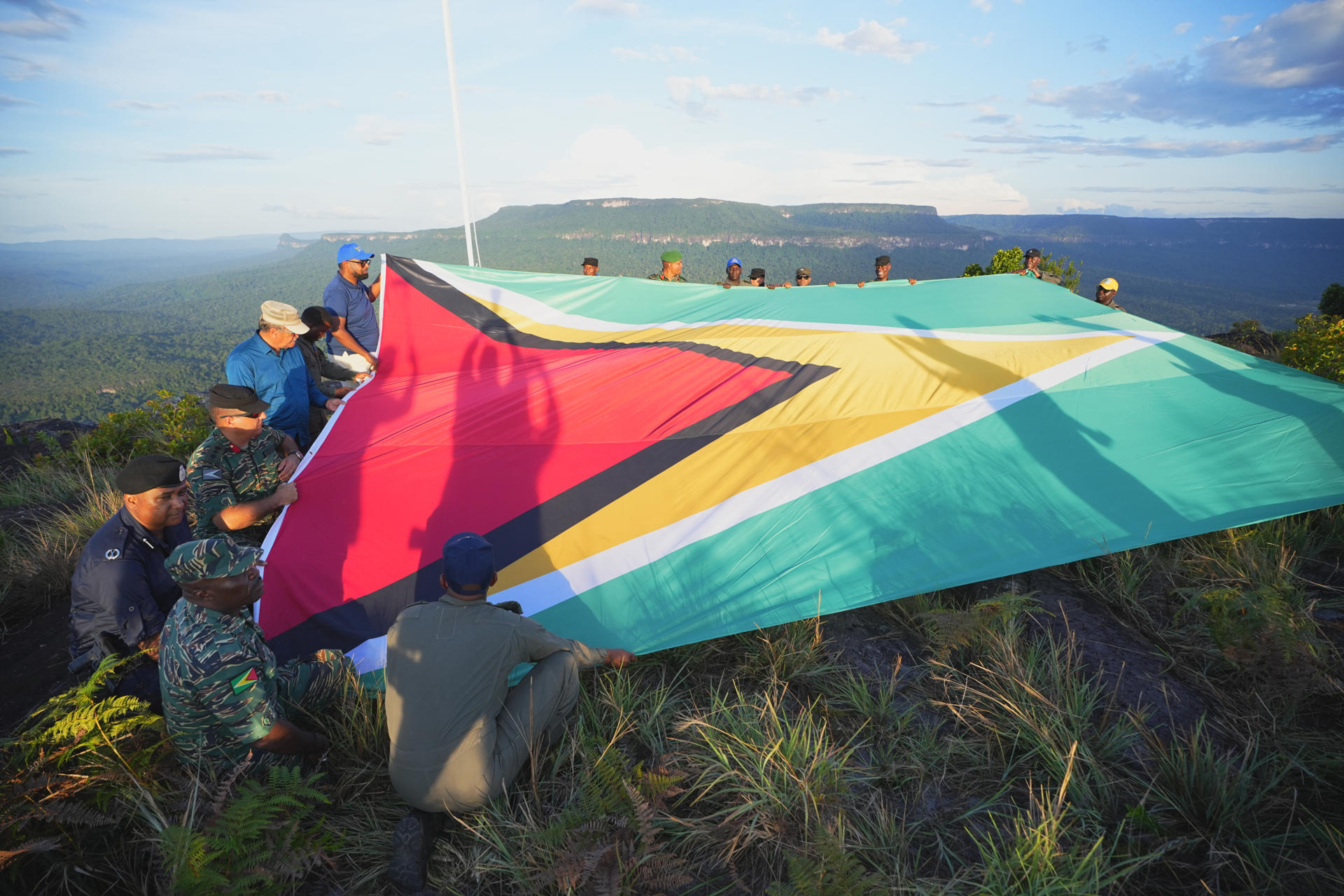 Fotografía cedida por la Presidencia de Guyana de hombres desplegando una bandera de Guyana en la montaña Pakrampa, en la aldea de Arau, región Esequibo (Guyana). EFE/ Presidencia de Guyana