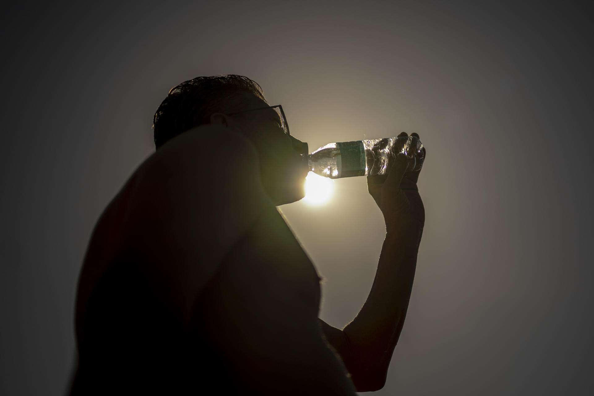 Un hombre bebe agua en la zona fluvial del río Miño y las termas de A Chavasqueira, este jueves en Ourense (Galicia), región que se prepara para el pico máximo del actual episodio extraordinario de altas temperaturas, más acordes con meses de pleno verano que con finales de mayo. EFE /Brais Lorenzo