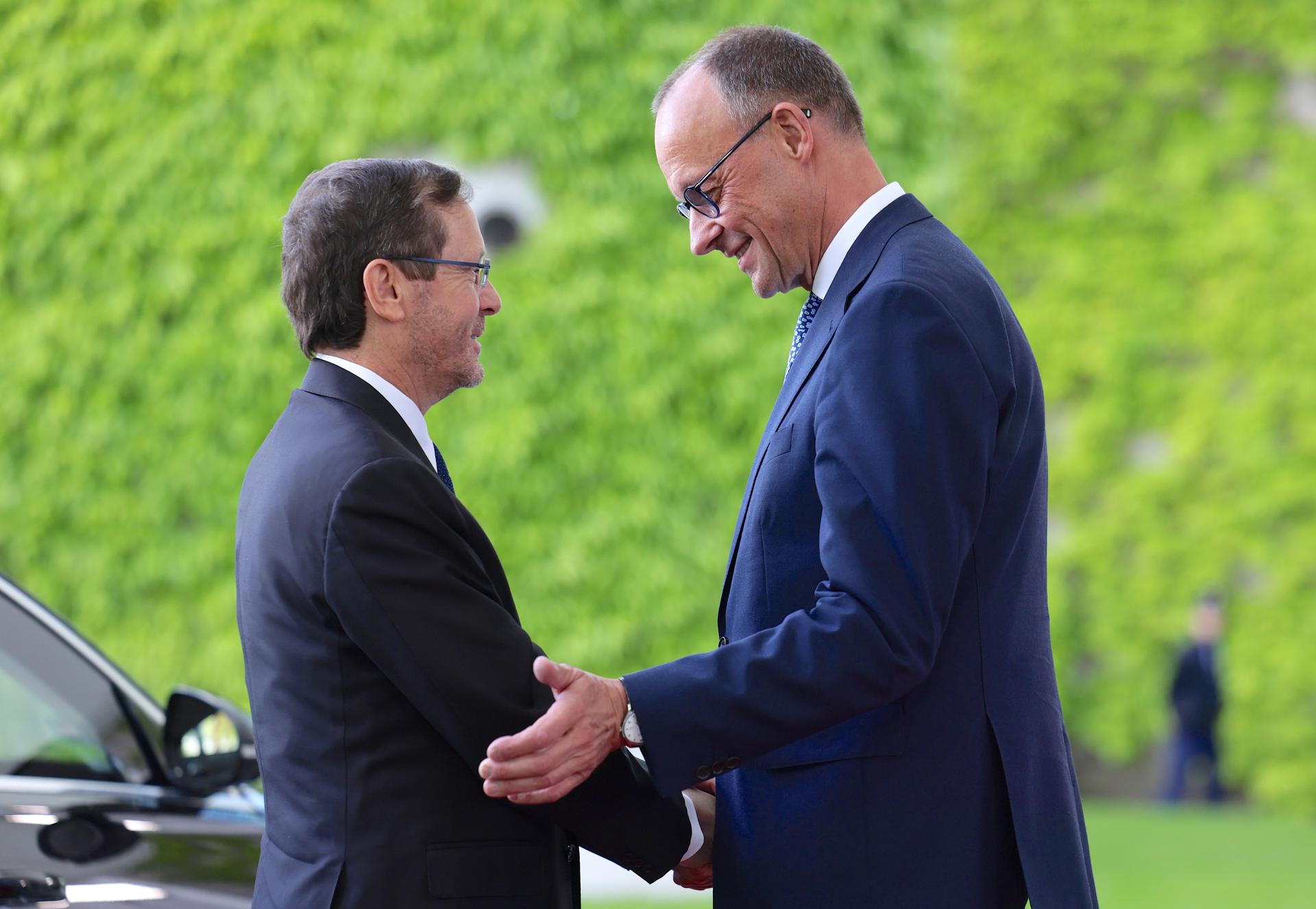 El canciller alemán Friedrich Merz (derecha) da la bienvenida al presidente israelí Isaac Herzog frente a la Cancillería en Berlín, Alemania, el 12 de mayo de 2025. Herzog visita Berlín para conmemorar los 60 años de relaciones diplomáticas entre los dos países. (Alemania) EFE/EPA/HANNIBAL HANSCHKE